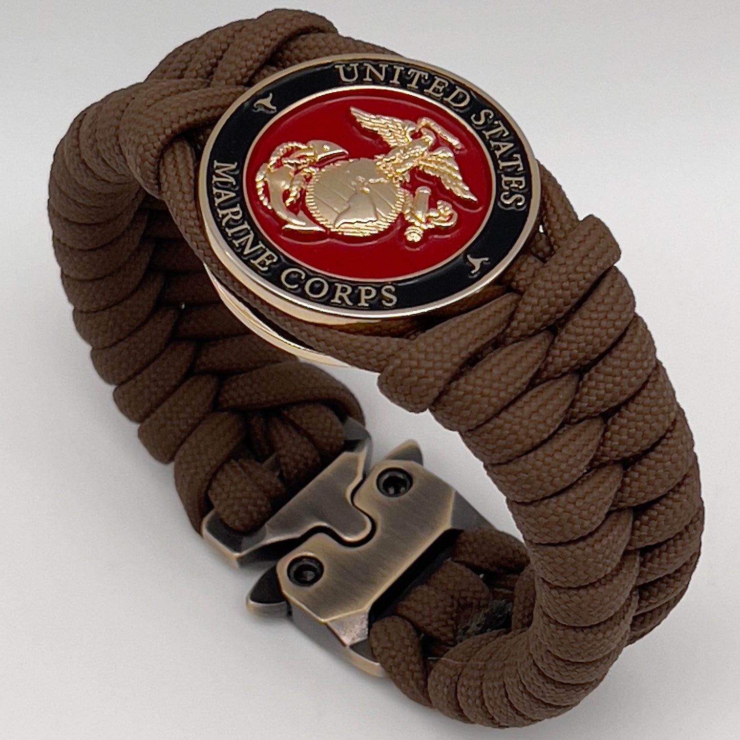 Thick, semi-rigid and comfortable braided United States Marine Corps bracelet featuring a 24K gold plated USMC Eagle Globe and Anchor medallion, a gold Cobra style tactical buckle and woven with Coyote Brown 550 paracord.
