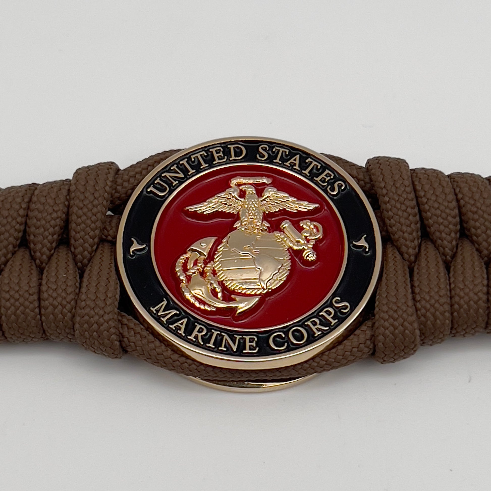 Thick, semi-rigid and comfortable braided United States Marine Corps bracelet featuring a 24K gold plated USMC Eagle Globe and Anchor medallion, a gold Cobra style tactical buckle and woven with Coyote Brown 550 paracord.