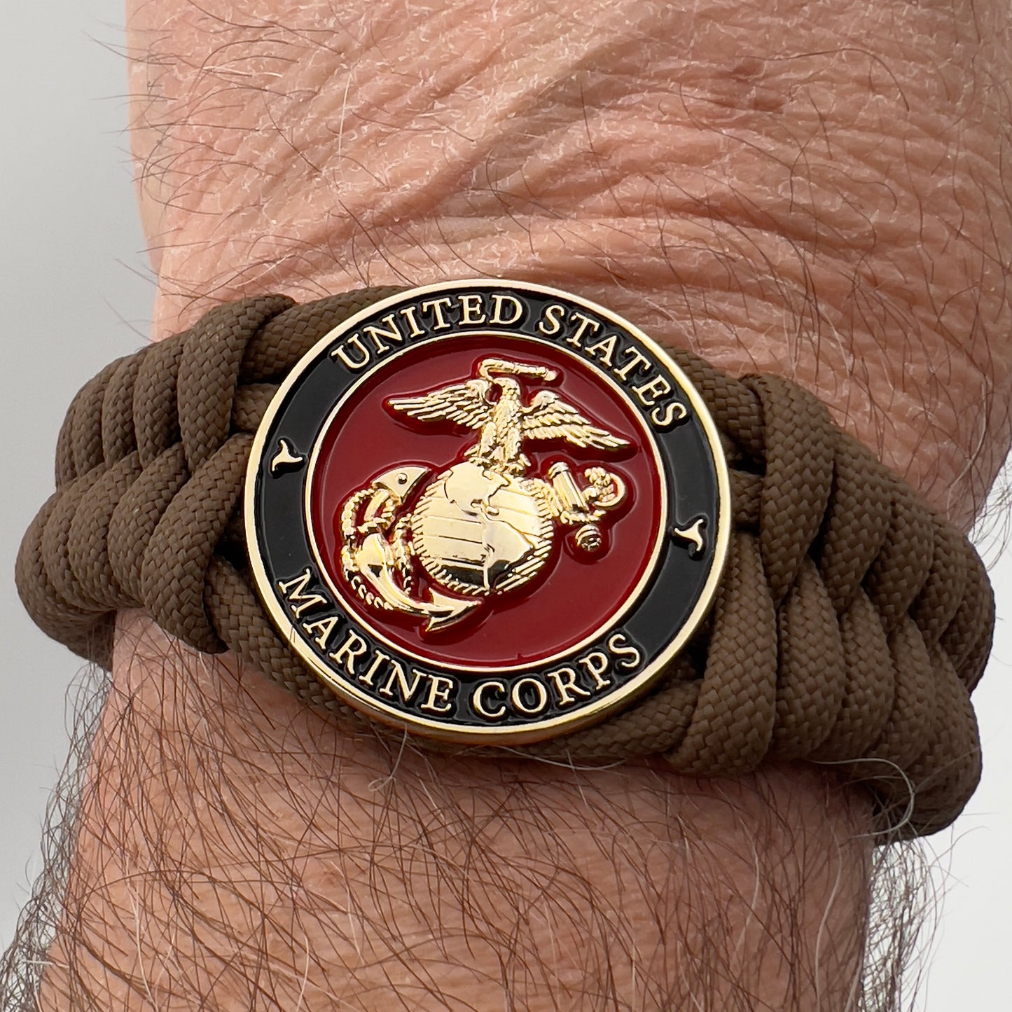 Thick, semi-rigid and comfortable braided United States Marine Corps bracelet featuring a 24K gold plated USMC Eagle Globe and Anchor medallion, a gold Cobra style tactical buckle and woven with Coyote Brown 550 paracord.
