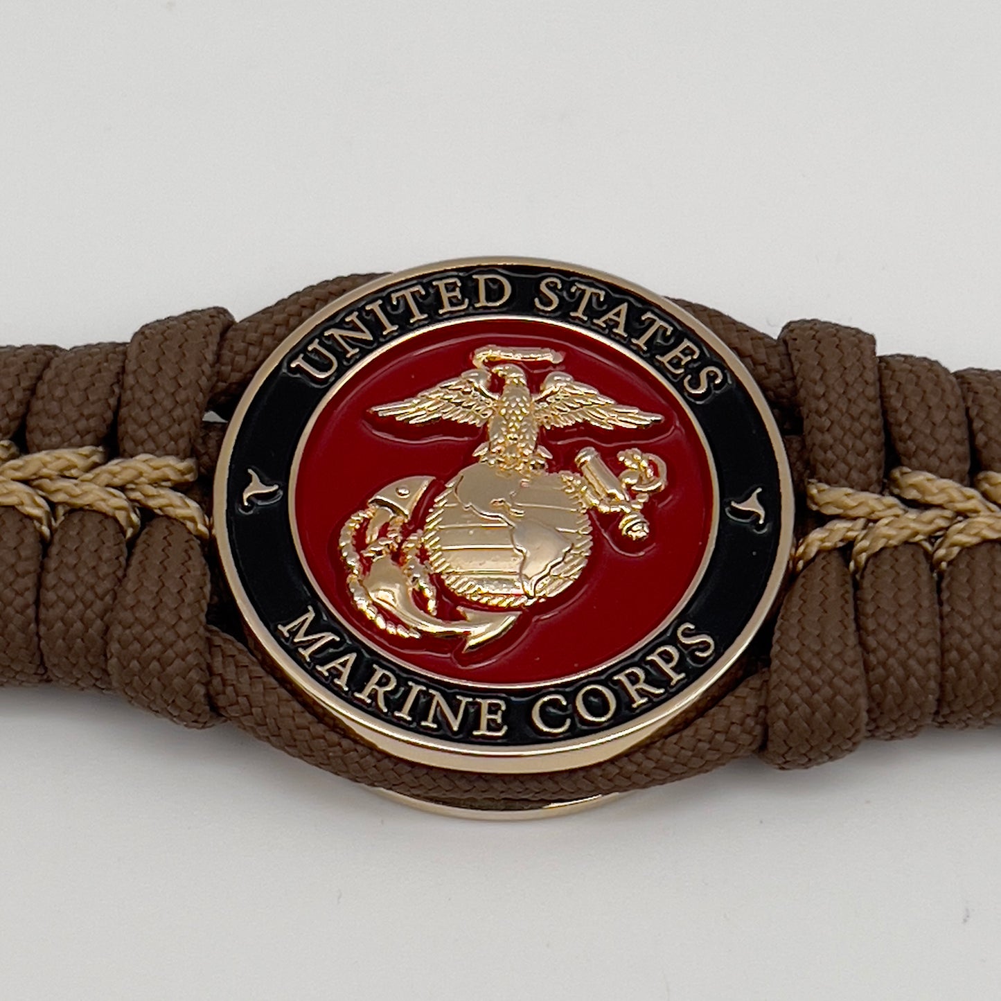 Thick, rigid and comfortable braided United States Marine Corps bracelet featuring a 24K gold plated USMC Eagle Globe and Anchor medallion, a gold Cobra style tactical buckle and woven with Coyote Brown 550 paracord and gold micro cord.