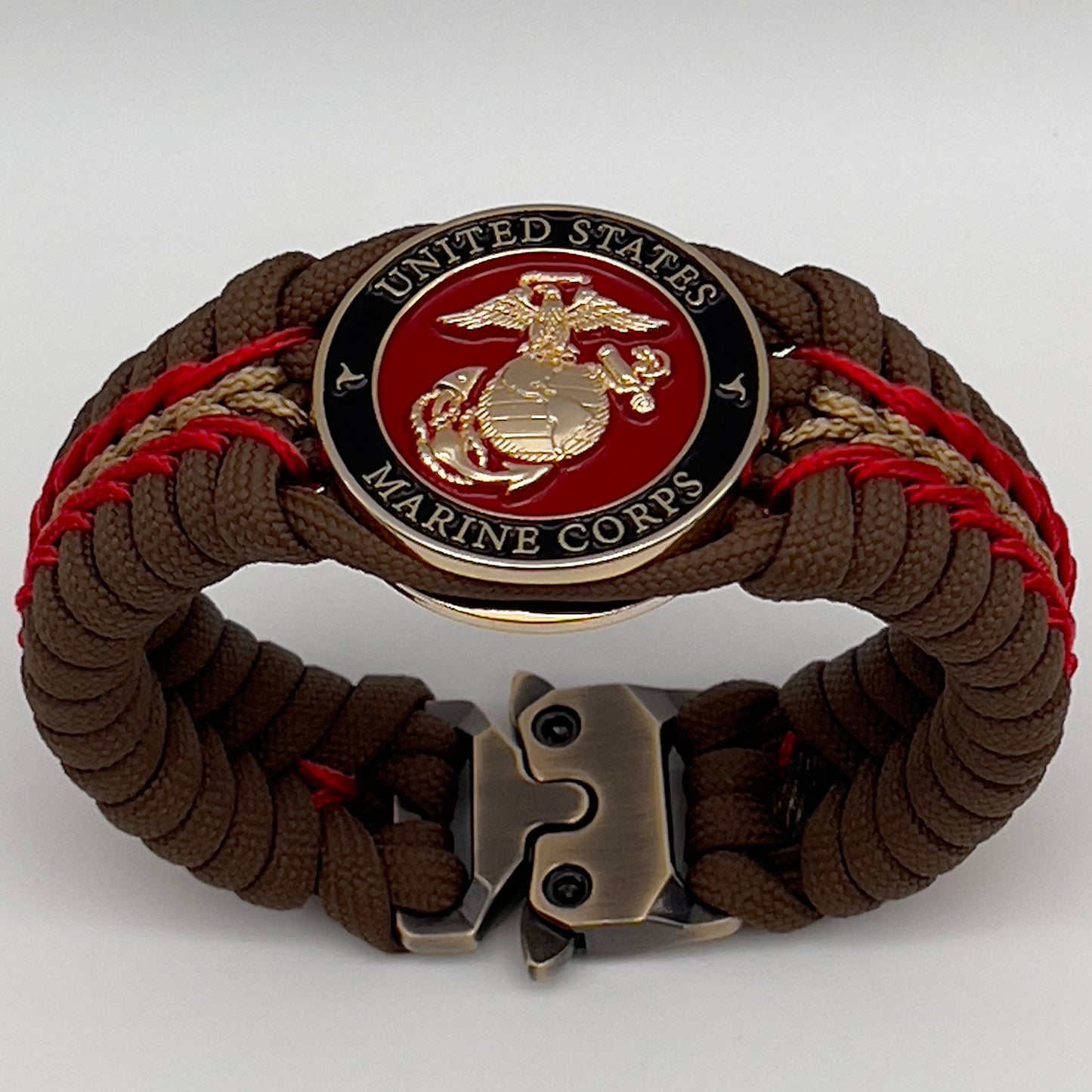 Thick, rigid and comfortable braided United States Marine Corps bracelet featuring a 24K gold plated USMC Eagle Globe and Anchor medallion, a gold Cobra style tactical buckle and woven with Coyote Brown 550 paracord and Imperial Red and gold micro cord.