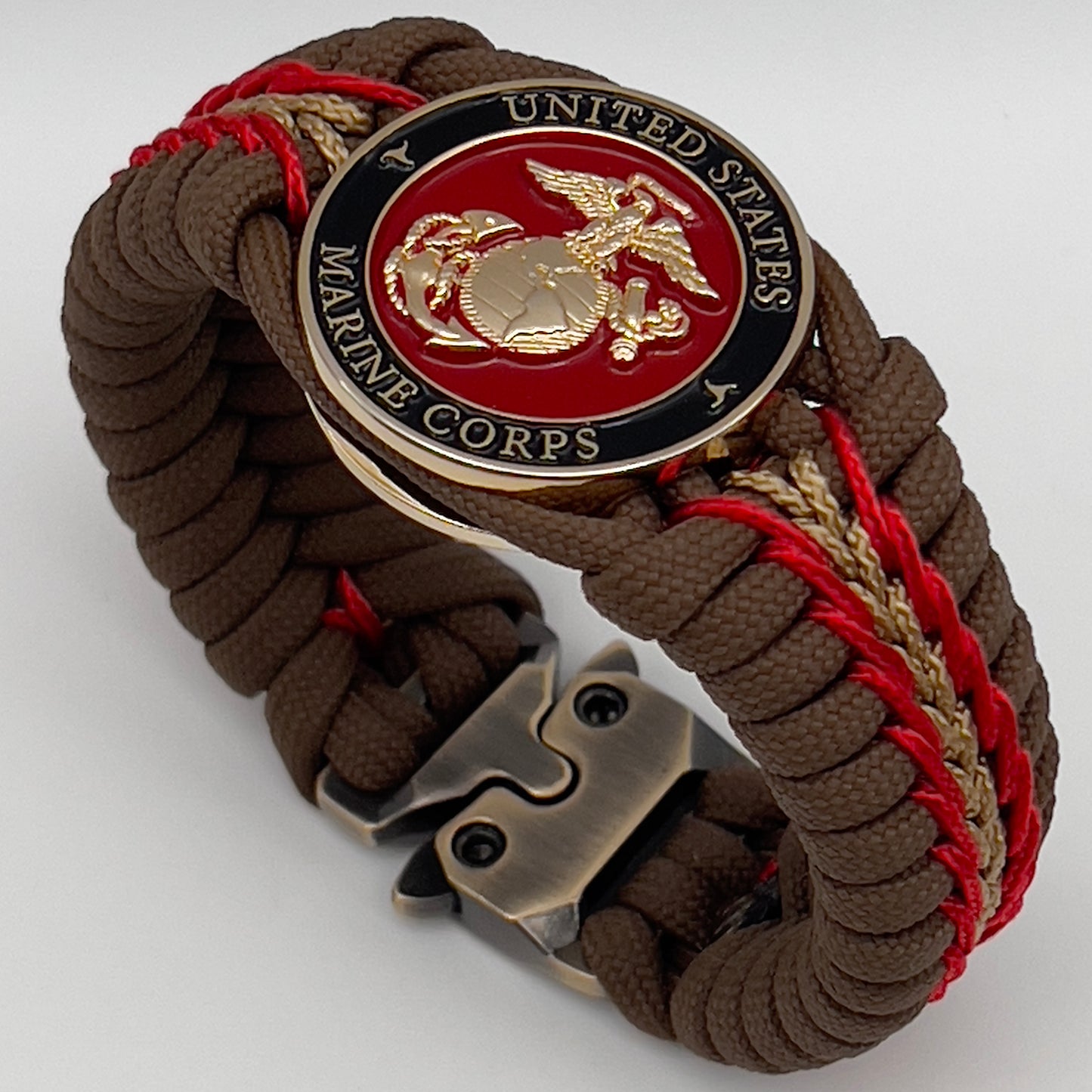 Thick, rigid and comfortable braided United States Marine Corps bracelet featuring a 24K gold plated USMC Eagle Globe and Anchor medallion, a gold Cobra style tactical buckle and woven with Coyote Brown 550 paracord and Imperial Red and gold micro cord.