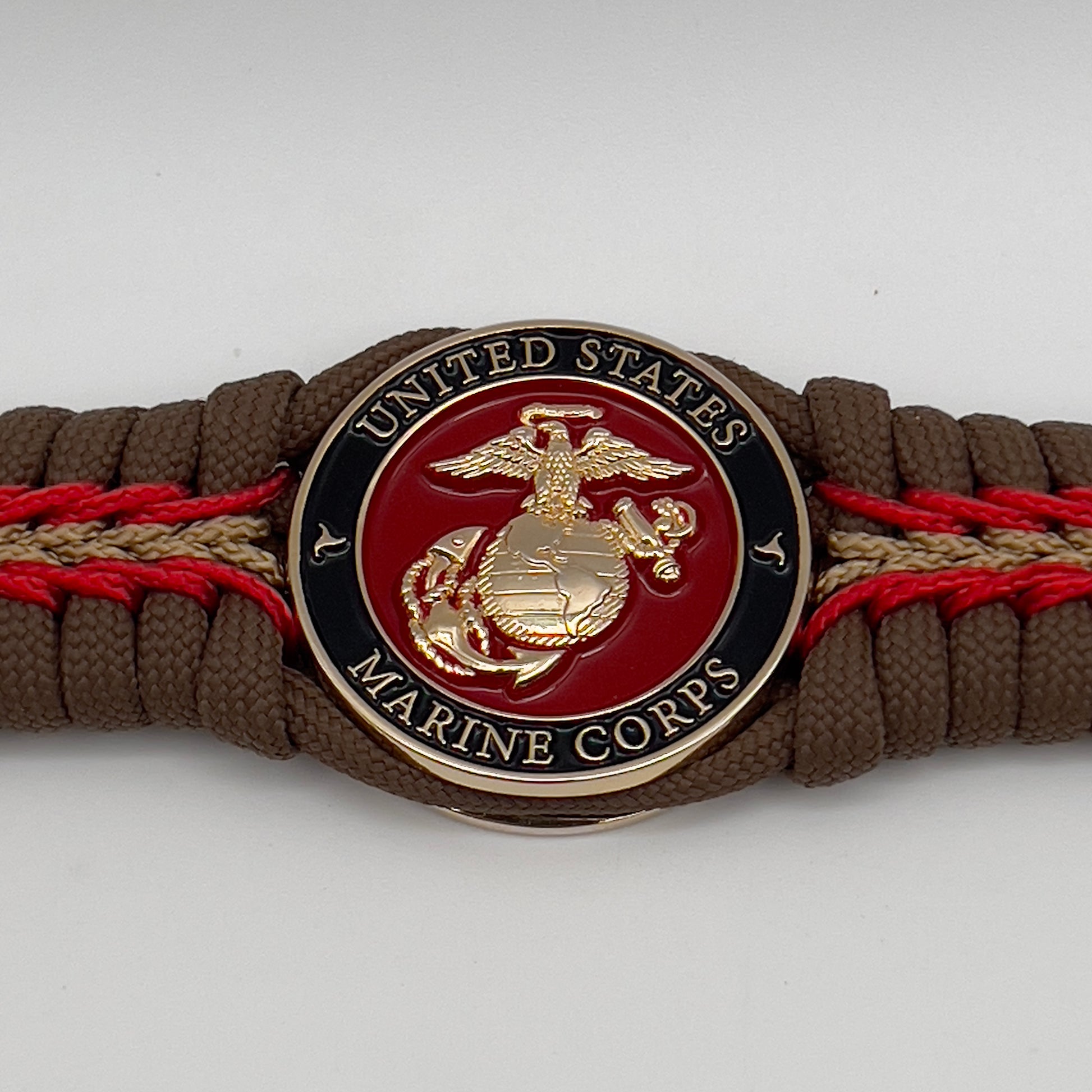 Thick, rigid and comfortable braided United States Marine Corps bracelet featuring a 24K gold plated USMC Eagle Globe and Anchor medallion, a gold Cobra style tactical buckle and woven with Coyote Brown 550 paracord and Imperial Red and gold micro cord.