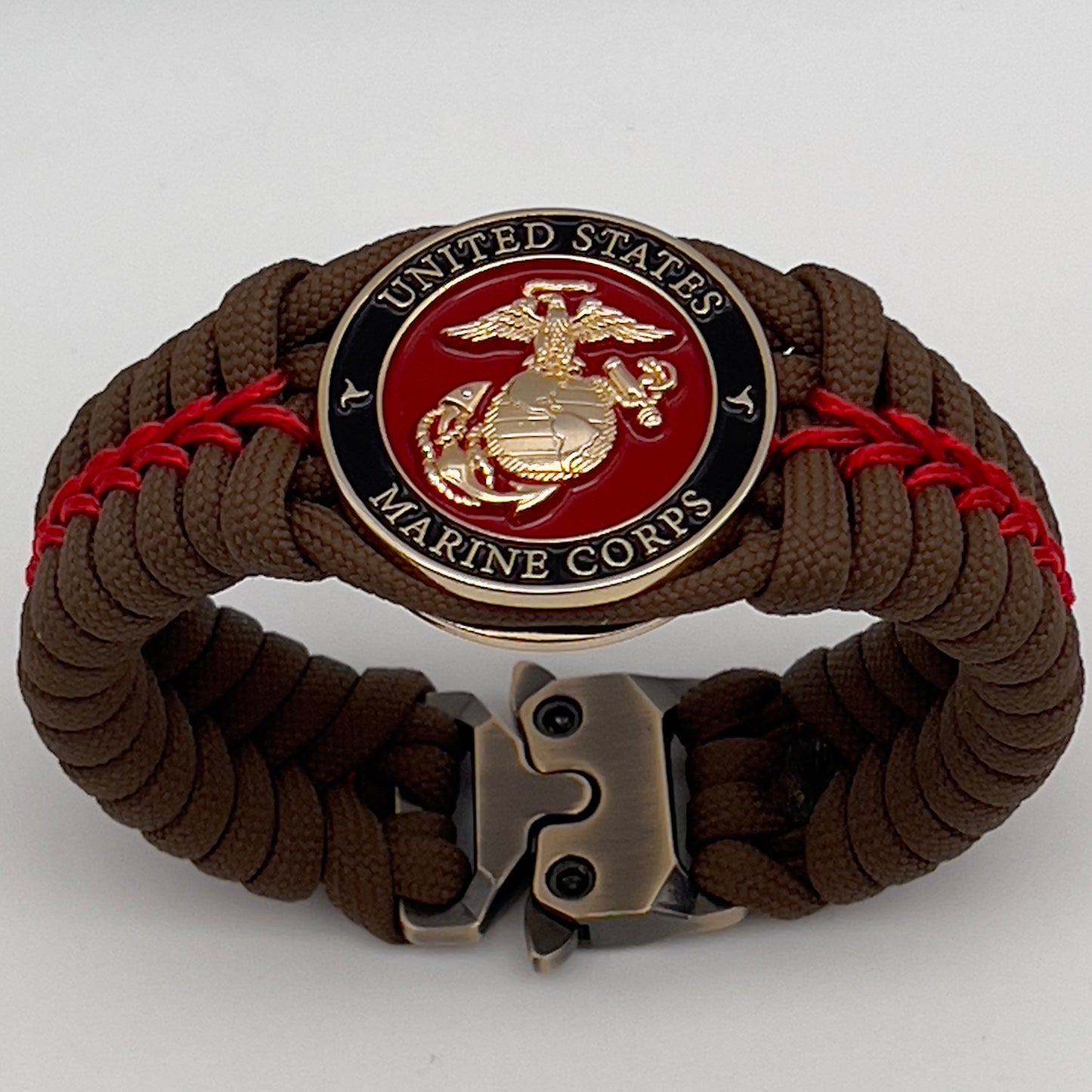 Thick, rigid and comfortable braided United States Marine Corps bracelet featuring a 24K gold plated USMC Eagle Globe and Anchor medallion, a gold Cobra style tactical buckle and woven with Coyote Brown 550 paracord and Imperial Red micro cord.