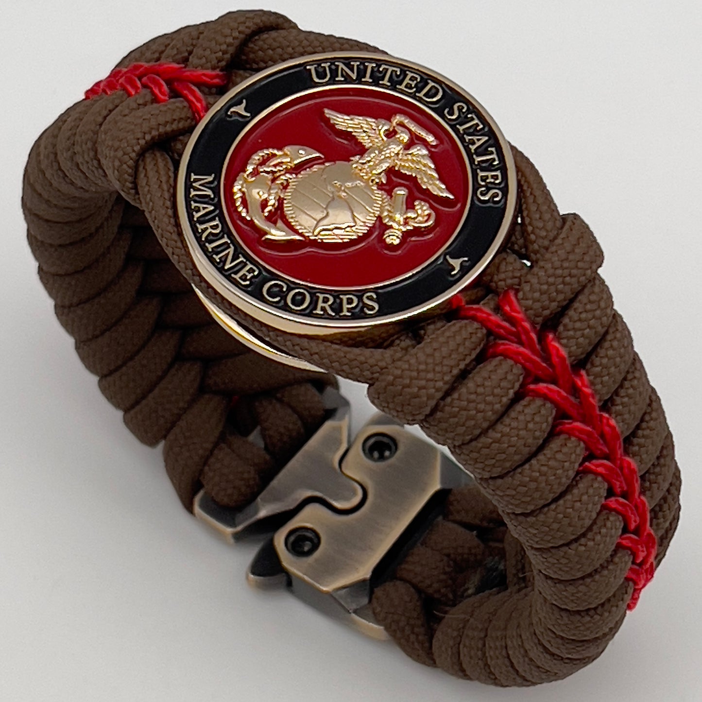 Thick, rigid and comfortable braided United States Marine Corps bracelet featuring a 24K gold plated USMC Eagle Globe and Anchor medallion, a gold Cobra style tactical buckle and woven with Coyote Brown 550 paracord and Imperial Red micro cord.