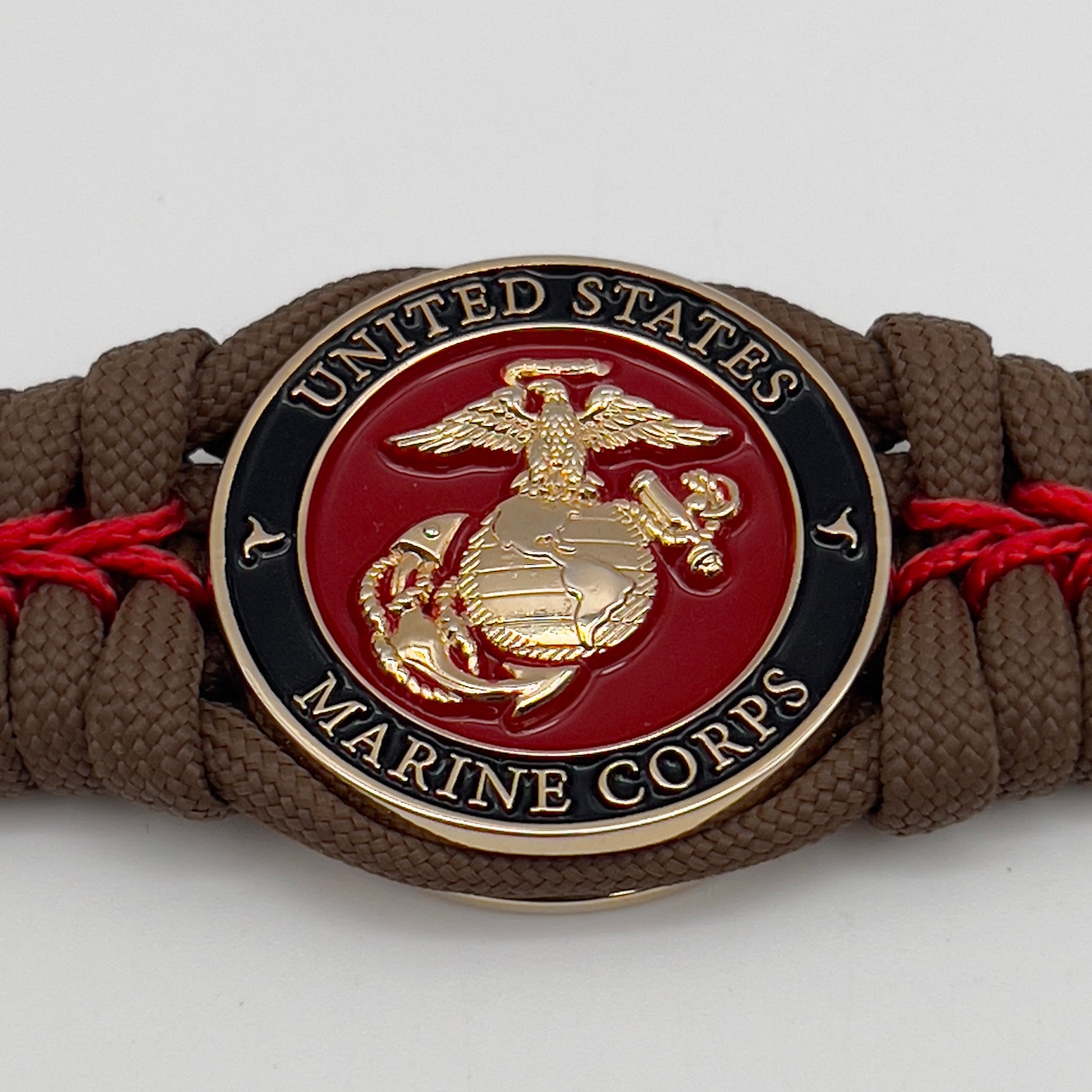 Thick, rigid and comfortable braided United States Marine Corps bracelet featuring a 24K gold plated USMC Eagle Globe and Anchor medallion, a gold Cobra style tactical buckle and woven with Coyote Brown 550 paracord and Imperial Red micro cord.