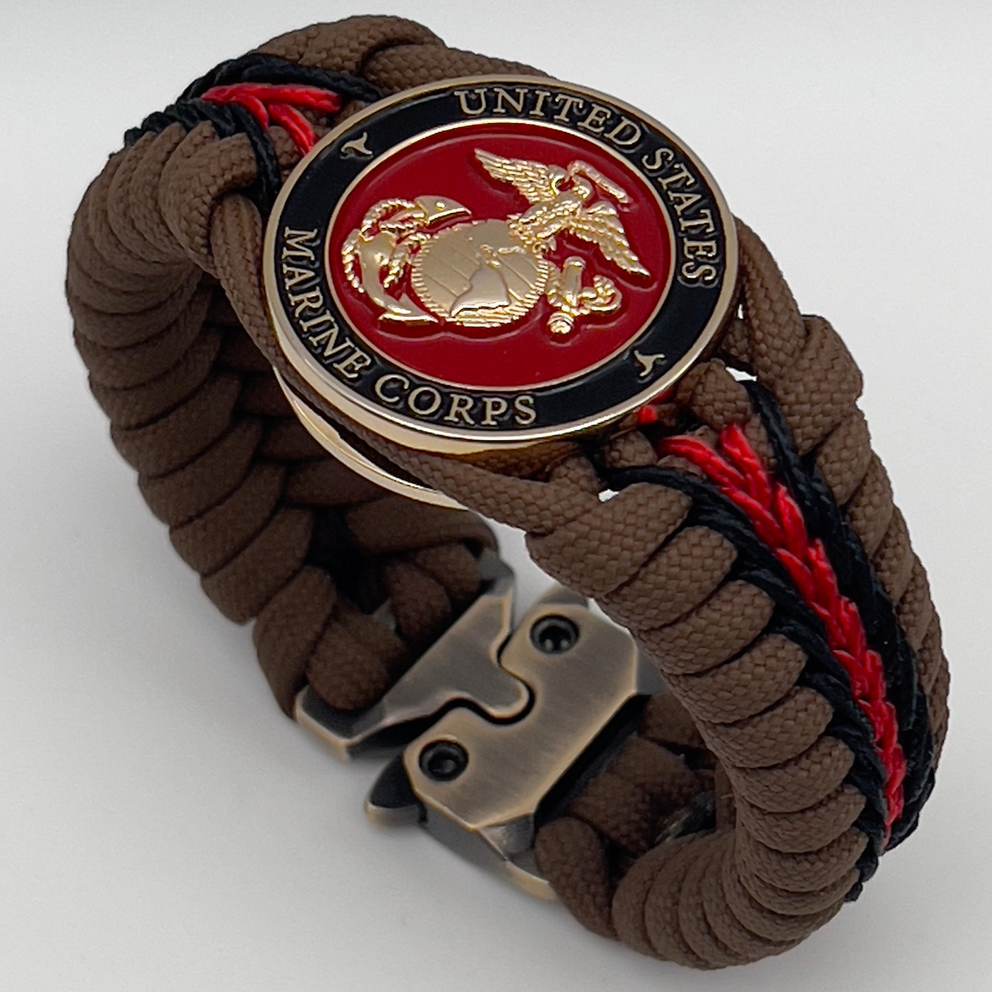 Thick, rigid and comfortable braided United States Marine Corps bracelet featuring a 24K gold plated USMC Eagle Globe and Anchor medallion, a gold Cobra style tactical buckle and woven with Coyote Brown 550 paracord and Imperial Red and black micro cord.