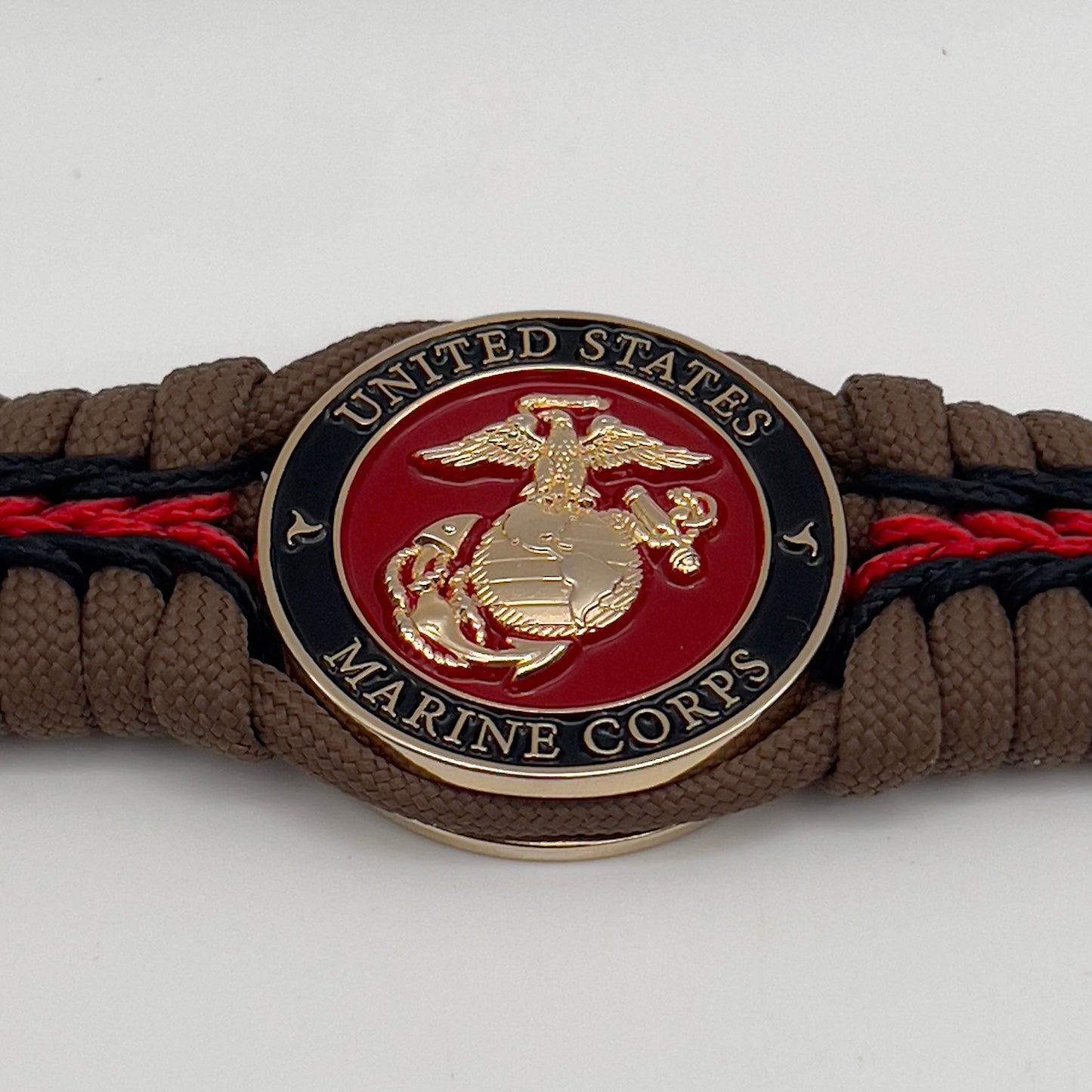 Thick, rigid and comfortable braided United States Marine Corps bracelet featuring a 24K gold plated USMC Eagle Globe and Anchor medallion, a gold Cobra style tactical buckle and woven with Coyote Brown 550 paracord and Imperial Red and black micro cord.