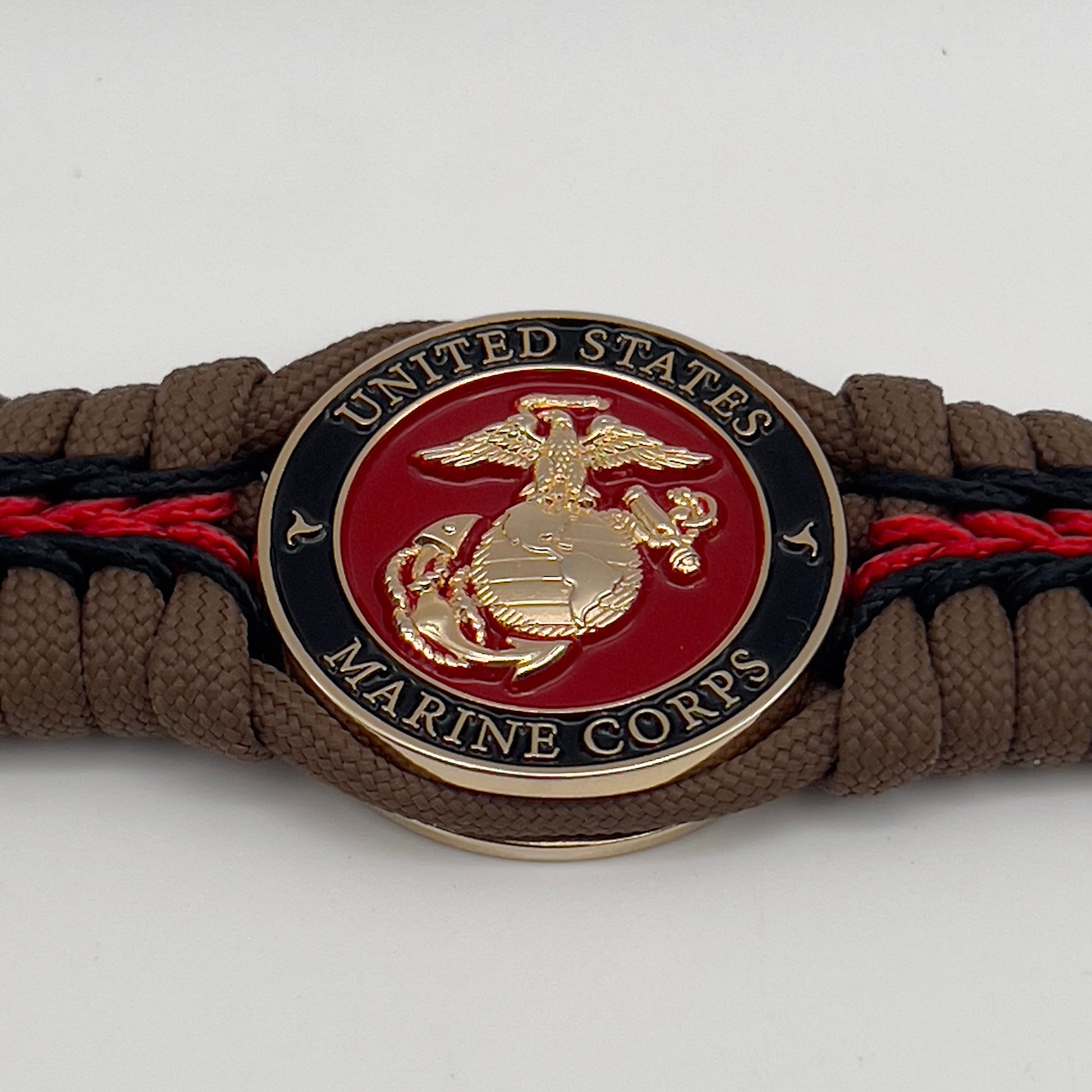 Thick, rigid and comfortable braided United States Marine Corps bracelet featuring a 24K gold plated USMC Eagle Globe and Anchor medallion, a gold Cobra style tactical buckle and woven with Coyote Brown 550 paracord and Imperial Red and black micro cord.