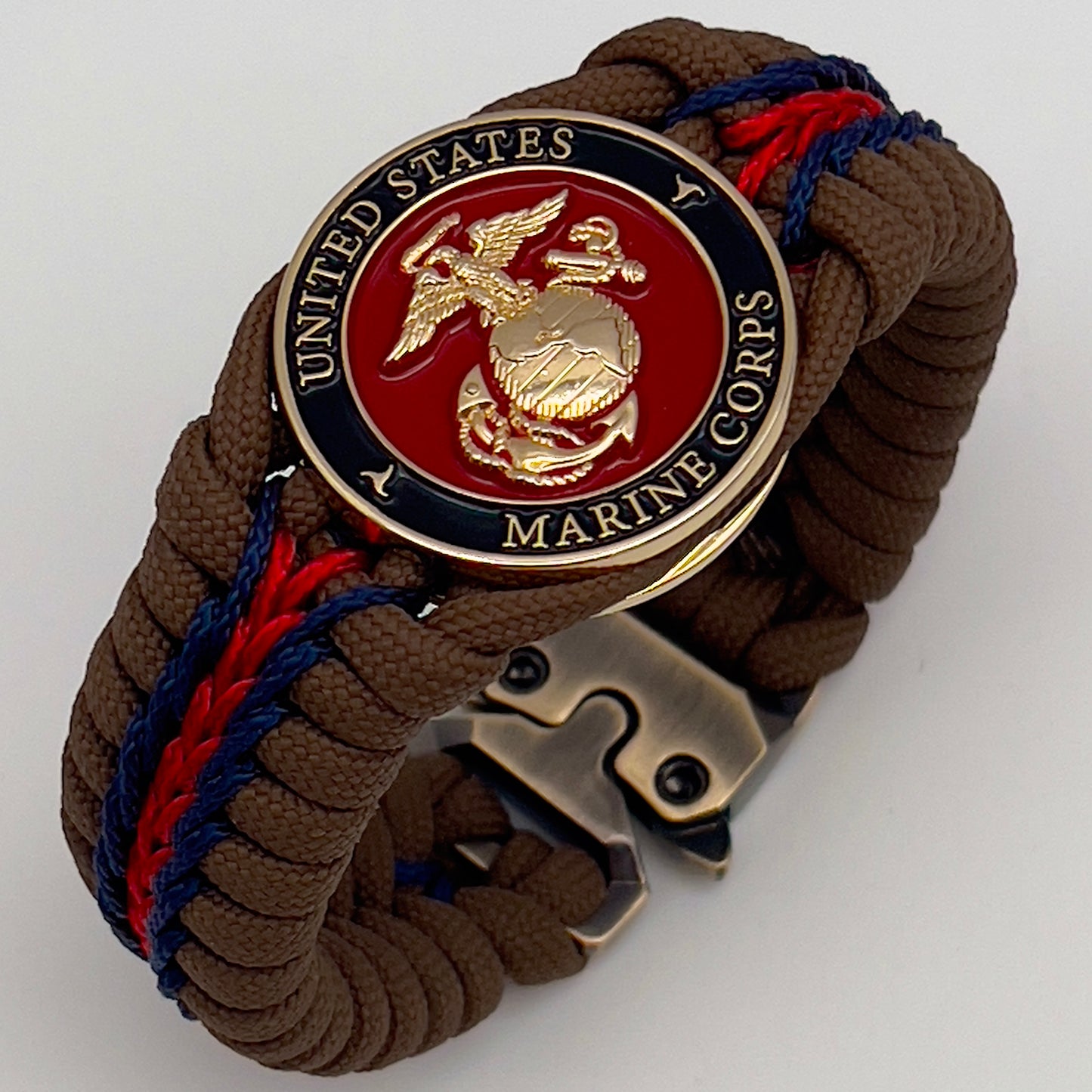 Thick, rigid and comfortable braided United States Marine Corps bracelet featuring a 24K gold plated USMC Eagle Globe and Anchor medallion, a gold Cobra style tactical buckle and woven with Coyote Brown 550 paracord and Imperial Red and Navy Blue micro cord.