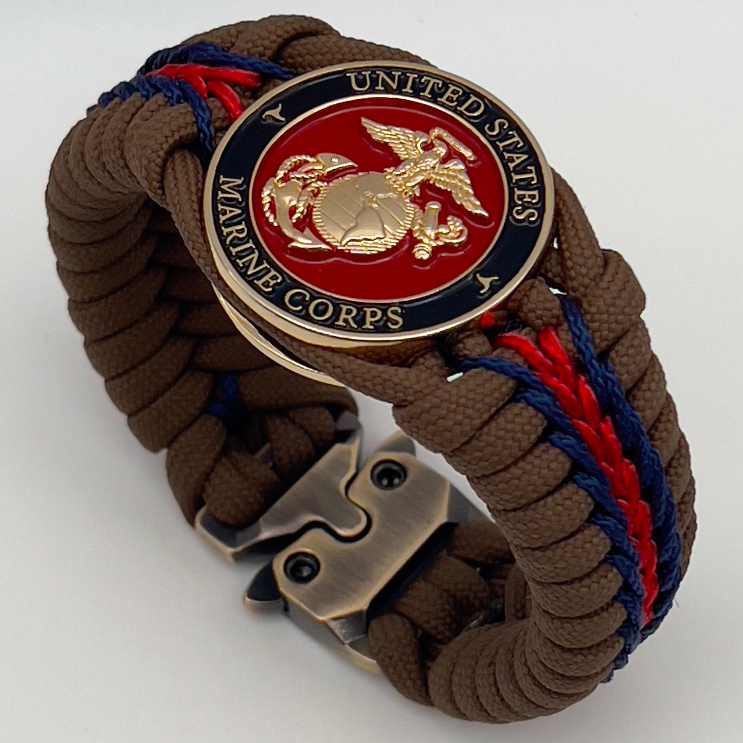 Thick, rigid and comfortable braided United States Marine Corps bracelet featuring a 24K gold plated USMC Eagle Globe and Anchor medallion, a gold Cobra style tactical buckle and woven with Coyote Brown 550 paracord and Imperial Red and Navy Blue micro cord.