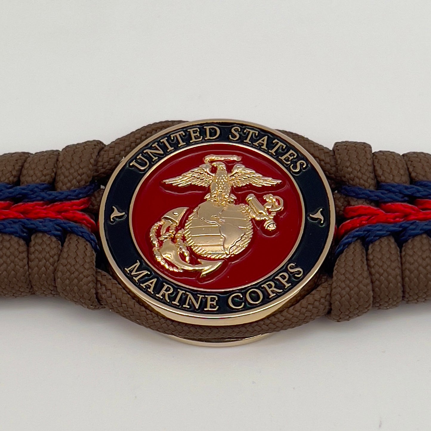 Thick, rigid and comfortable braided United States Marine Corps bracelet featuring a 24K gold plated USMC Eagle Globe and Anchor medallion, a gold Cobra style tactical buckle and woven with Coyote Brown 550 paracord and Imperial Red and Navy Blue micro cord.