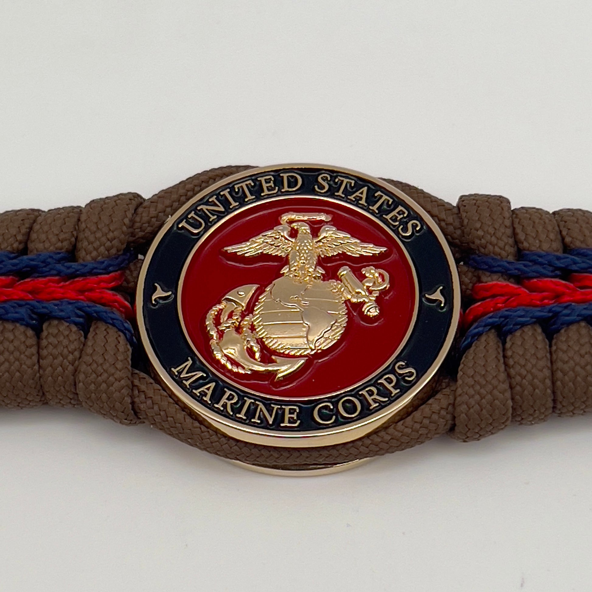 Thick, rigid and comfortable braided United States Marine Corps bracelet featuring a 24K gold plated USMC Eagle Globe and Anchor medallion, a gold Cobra style tactical buckle and woven with Coyote Brown 550 paracord and Imperial Red and Navy Blue micro cord.