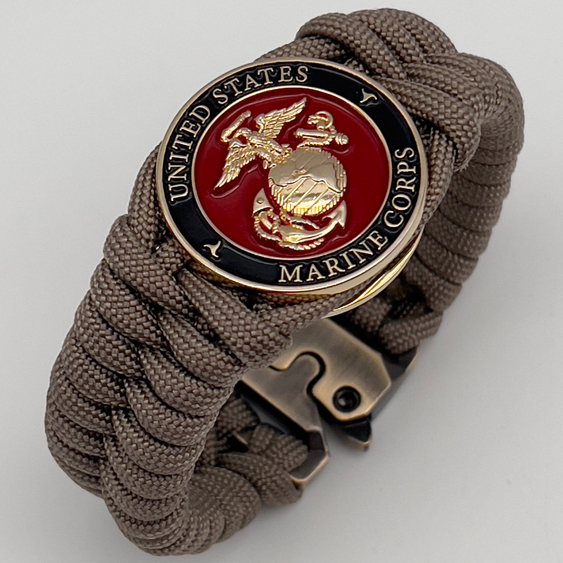 Thick, semi-rigid and comfortable braided United States Marine Corps bracelet featuring a 24K gold plated USMC Eagle Globe and Anchor medallion, a gold Cobra style tactical buckle and woven with tan 550 paracord.
