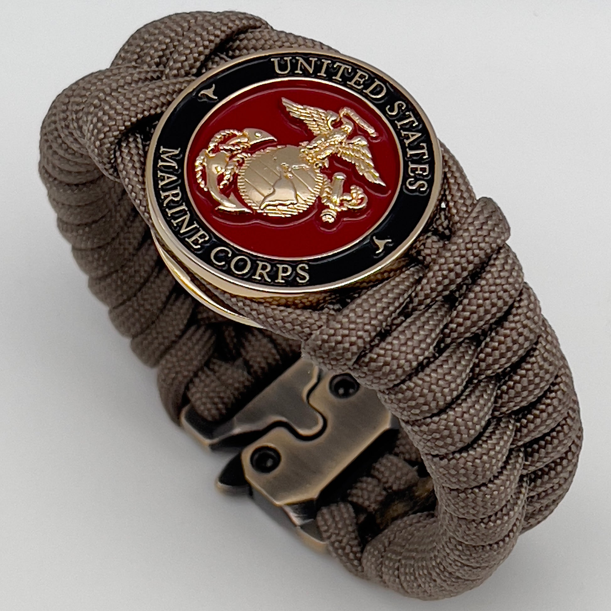 Thick, semi-rigid and comfortable braided United States Marine Corps bracelet featuring a 24K gold plated USMC Eagle Globe and Anchor medallion, a gold Cobra style tactical buckle and woven with tan 550 paracord.