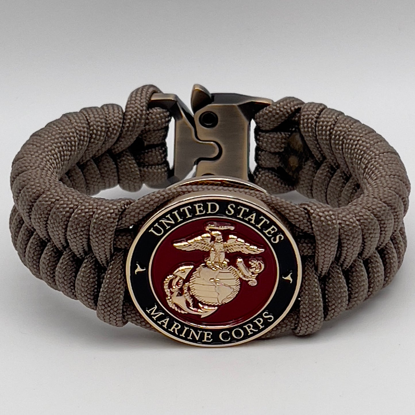 Thick, semi-rigid and comfortable braided United States Marine Corps bracelet featuring a 24K gold plated USMC Eagle Globe and Anchor medallion, a gold Cobra style tactical buckle and woven with tan 550 paracord.