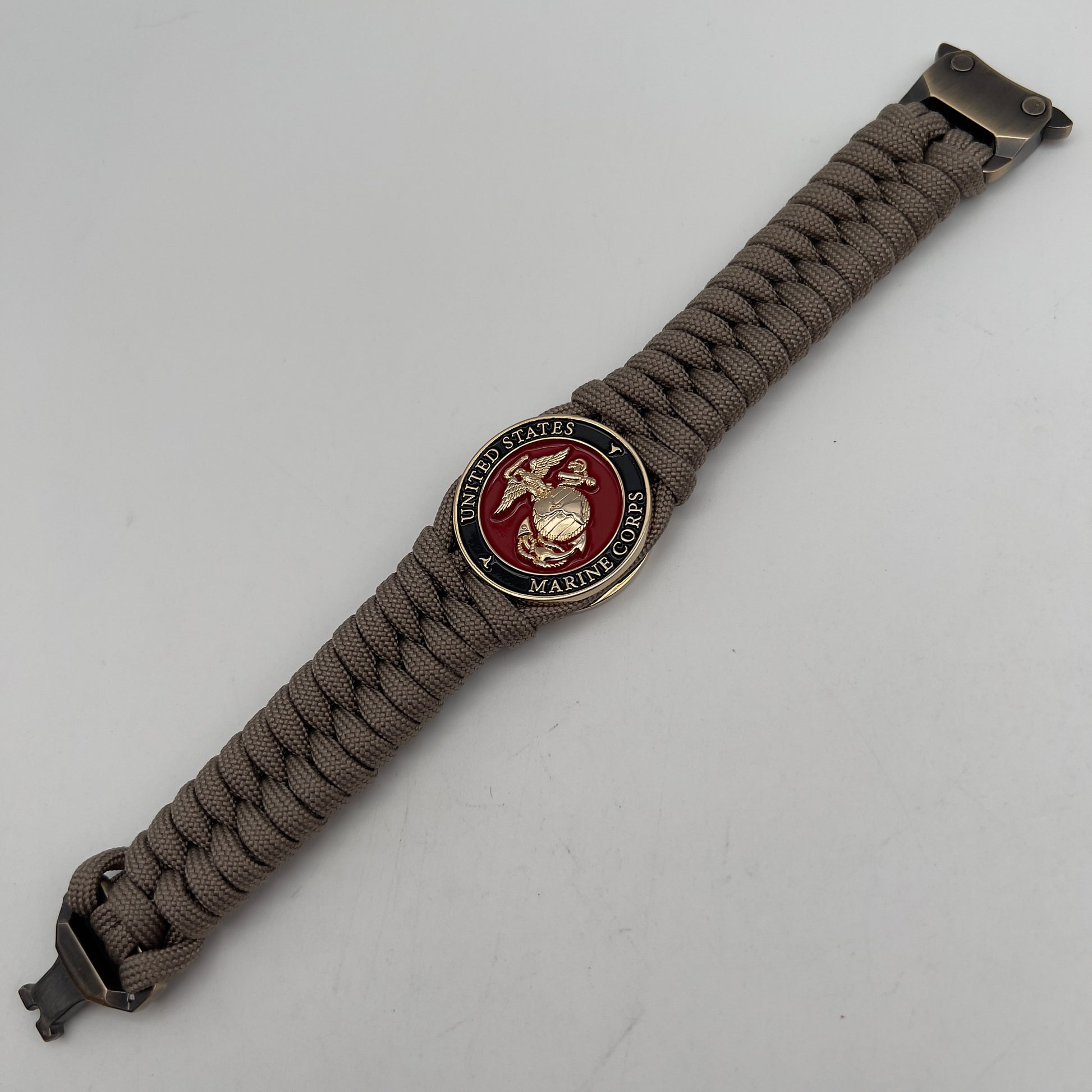 Thick, semi-rigid and comfortable braided United States Marine Corps bracelet featuring a 24K gold plated USMC Eagle Globe and Anchor medallion, a gold Cobra style tactical buckle and woven with tan 550 paracord.