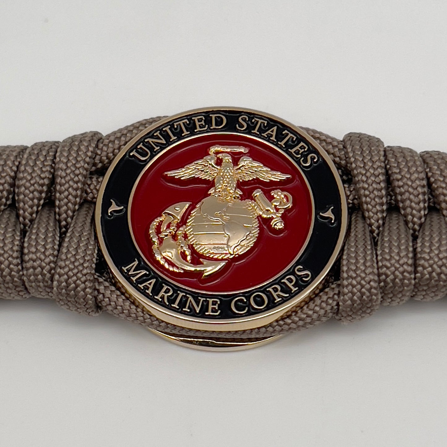 Thick, semi-rigid and comfortable braided United States Marine Corps bracelet featuring a 24K gold plated USMC Eagle Globe and Anchor medallion, a gold Cobra style tactical buckle and woven with tan 550 paracord.