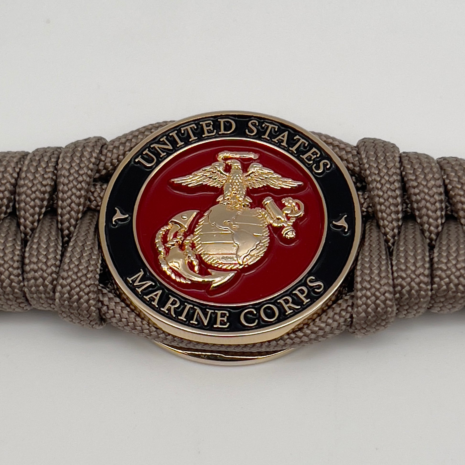 Thick, semi-rigid and comfortable braided United States Marine Corps bracelet featuring a 24K gold plated USMC Eagle Globe and Anchor medallion, a gold Cobra style tactical buckle and woven with tan 550 paracord.