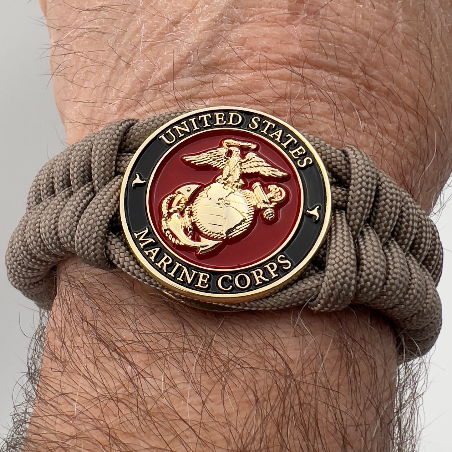 Thick, semi-rigid and comfortable braided United States Marine Corps bracelet featuring a 24K gold plated USMC Eagle Globe and Anchor medallion, a gold Cobra style tactical buckle and woven with tan 550 paracord.