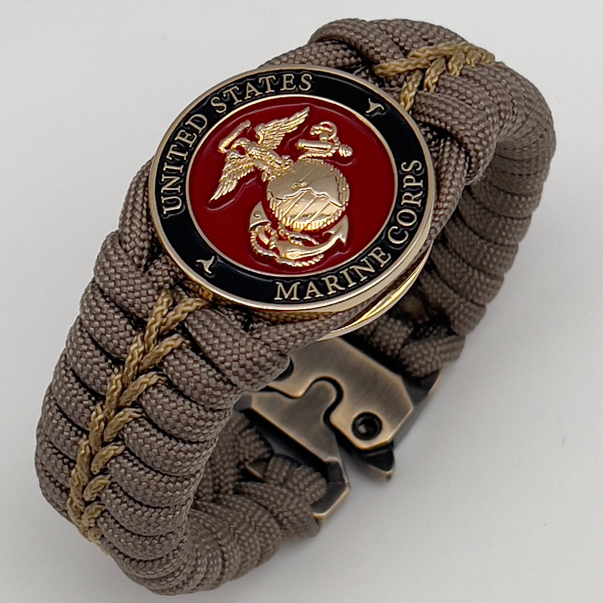 Thick, semi-rigid and comfortable braided United States Marine Corps bracelet featuring a 24K gold plated USMC Eagle Globe and Anchor medallion, a gold Cobra style tactical buckle and woven with tan 550 paracord and gold micro cord.