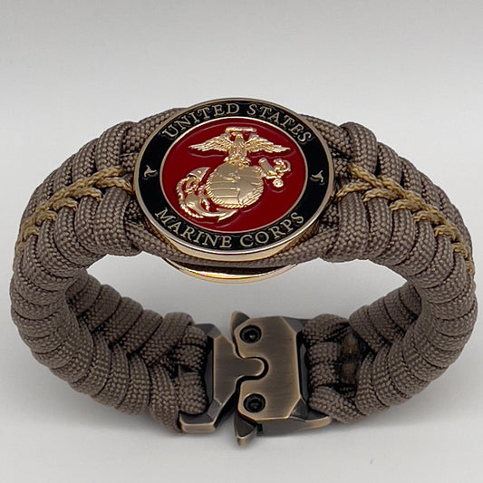 Thick, semi-rigid and comfortable braided United States Marine Corps bracelet featuring a 24K gold plated USMC Eagle Globe and Anchor medallion, a gold Cobra style tactical buckle and woven with tan 550 paracord and gold micro cord.