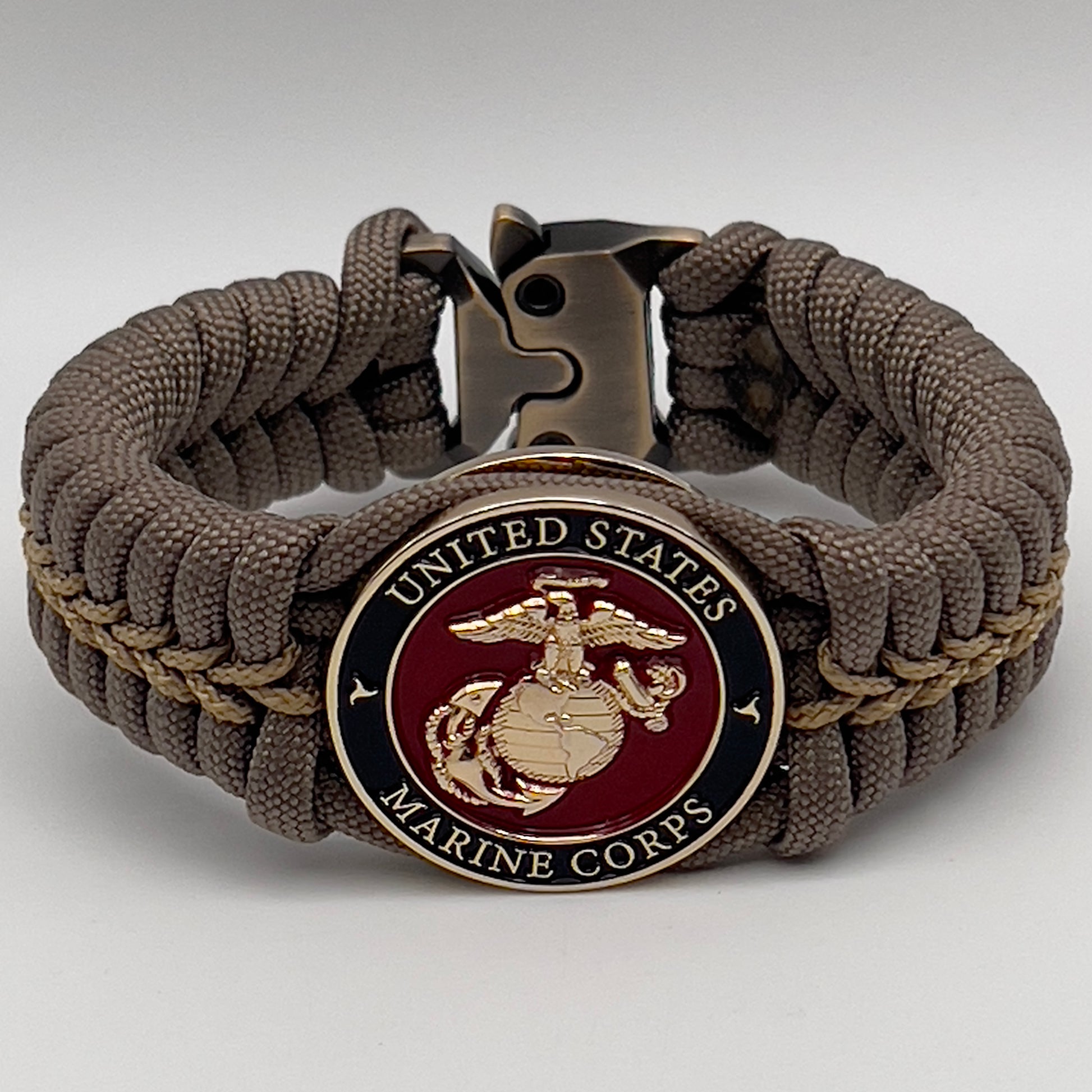 Thick, semi-rigid and comfortable braided United States Marine Corps bracelet featuring a 24K gold plated USMC Eagle Globe and Anchor medallion, a gold Cobra style tactical buckle and woven with tan 550 paracord and gold micro cord.