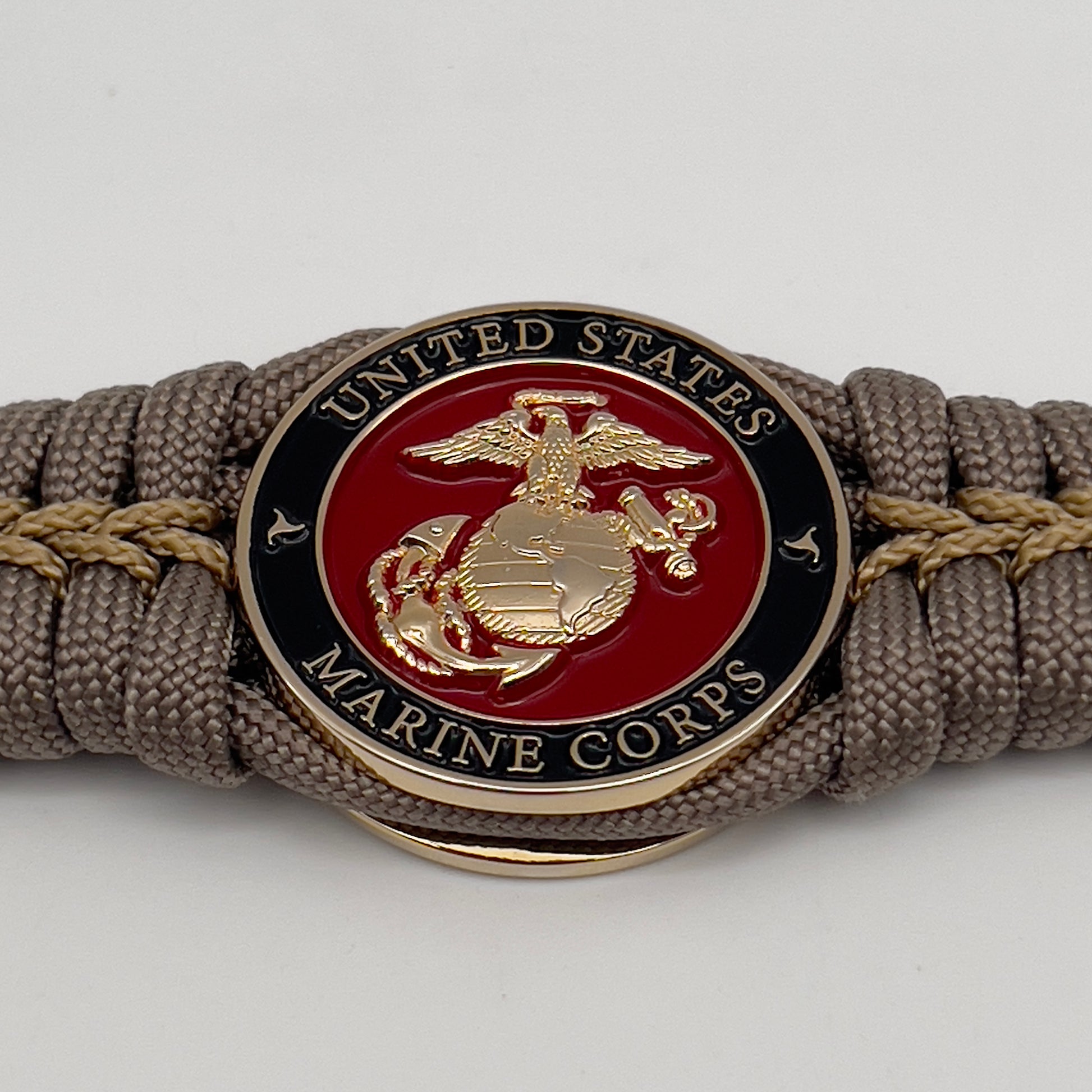 Thick, semi-rigid and comfortable braided United States Marine Corps bracelet featuring a 24K gold plated USMC Eagle Globe and Anchor medallion, a gold Cobra style tactical buckle and woven with tan 550 paracord and gold micro cord.