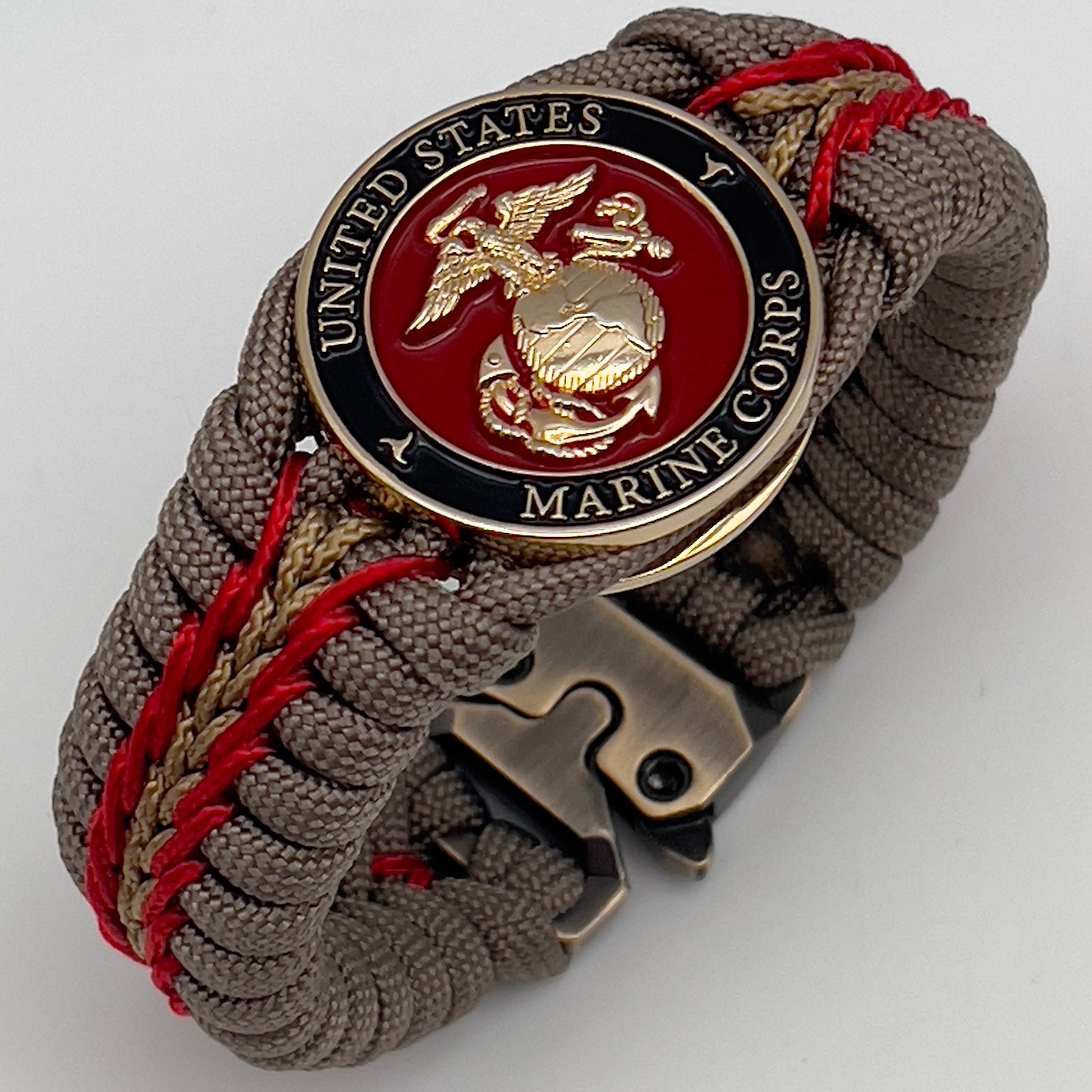Thick, rigid and comfortable braided United States Marine Corps bracelet featuring a 24K gold plated USMC Eagle Globe and Anchor medallion, a gold Cobra style tactical buckle and woven with tan 550 paracord and Imperial Red and gold micro cord.