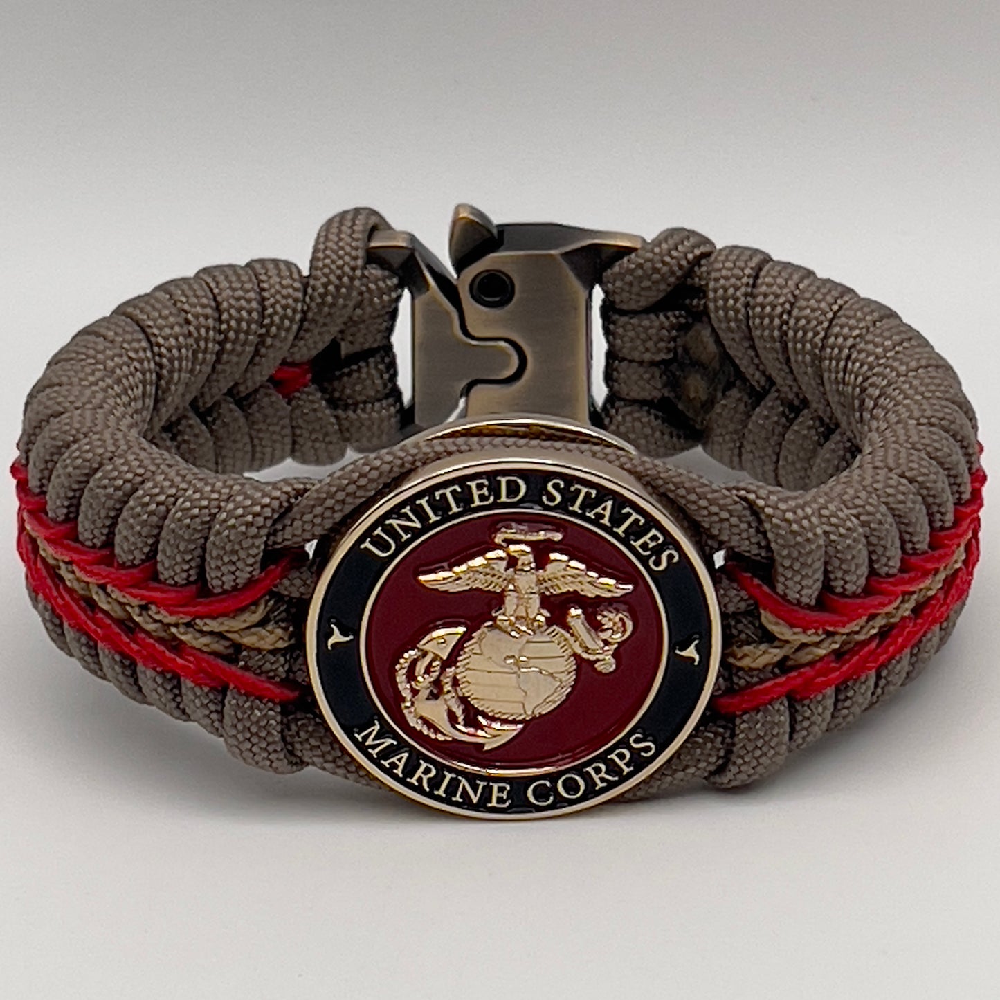 Thick, rigid and comfortable braided United States Marine Corps bracelet featuring a 24K gold plated USMC Eagle Globe and Anchor medallion, a gold Cobra style tactical buckle and woven with tan 550 paracord and Imperial Red and gold micro cord.