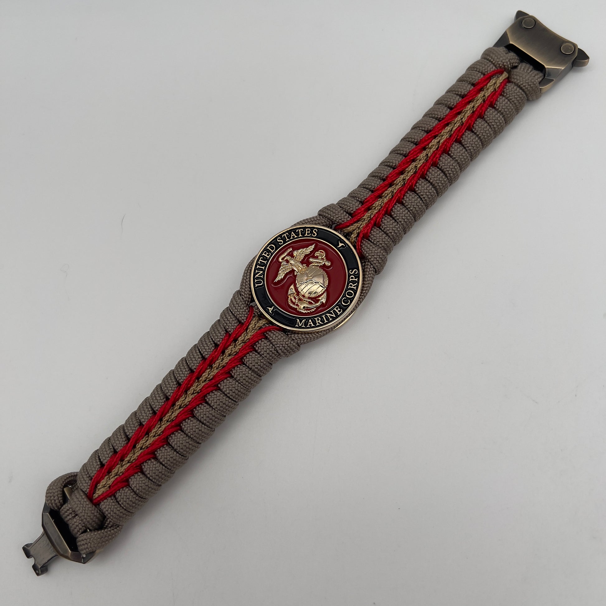 Thick, rigid and comfortable braided United States Marine Corps bracelet featuring a 24K gold plated USMC Eagle Globe and Anchor medallion, a gold Cobra style tactical buckle and woven with tan 550 paracord and Imperial Red and gold micro cord.