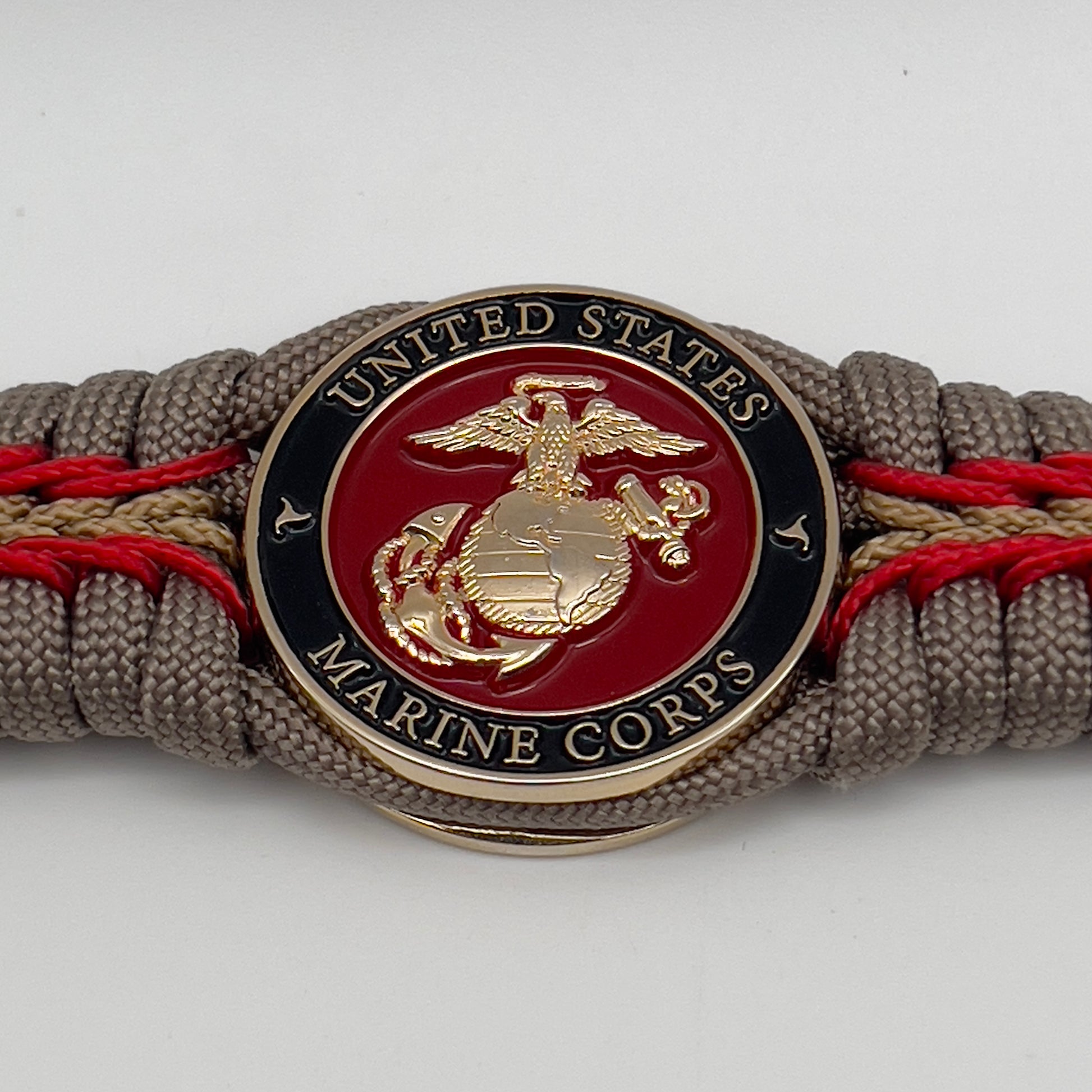 Thick, rigid and comfortable braided United States Marine Corps bracelet featuring a 24K gold plated USMC Eagle Globe and Anchor medallion, a gold Cobra style tactical buckle and woven with tan 550 paracord and Imperial Red and gold micro cord.