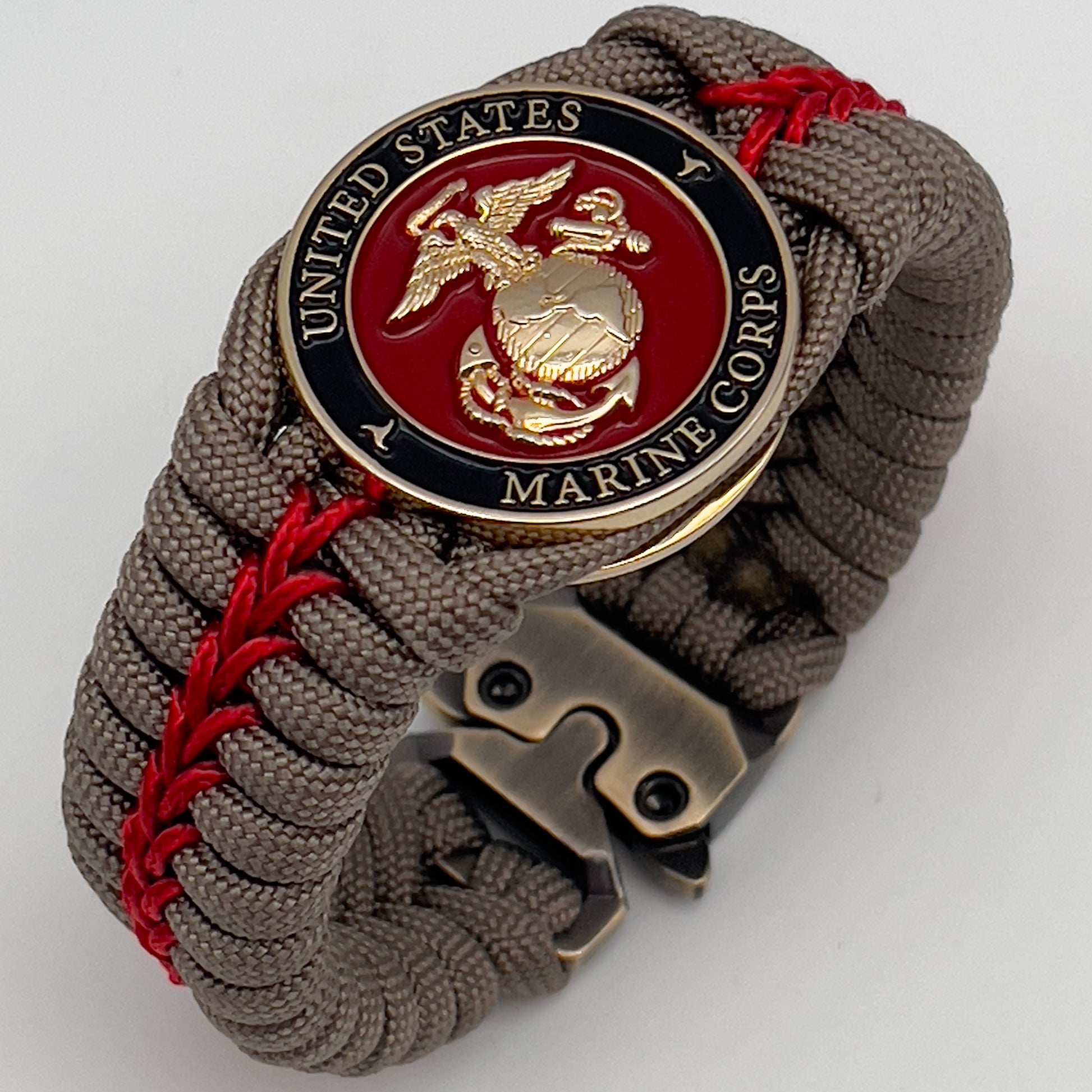 Thick, rigid and comfortable braided United States Marine Corps bracelet featuring a 24K gold plated USMC Eagle Globe and Anchor medallion, a gold Cobra style tactical buckle and woven with tan 550 paracord and Imperial Red micro cord.