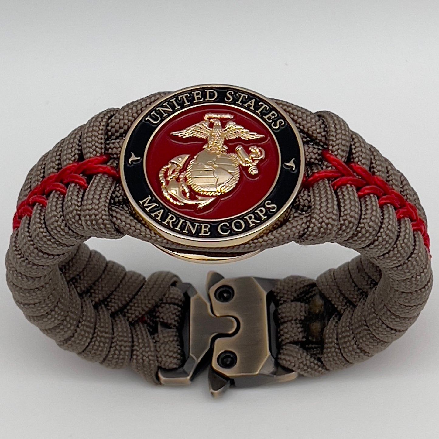 Thick, rigid and comfortable braided United States Marine Corps bracelet featuring a 24K gold plated USMC Eagle Globe and Anchor medallion, a gold Cobra style tactical buckle and woven with tan 550 paracord and Imperial Red micro cord.