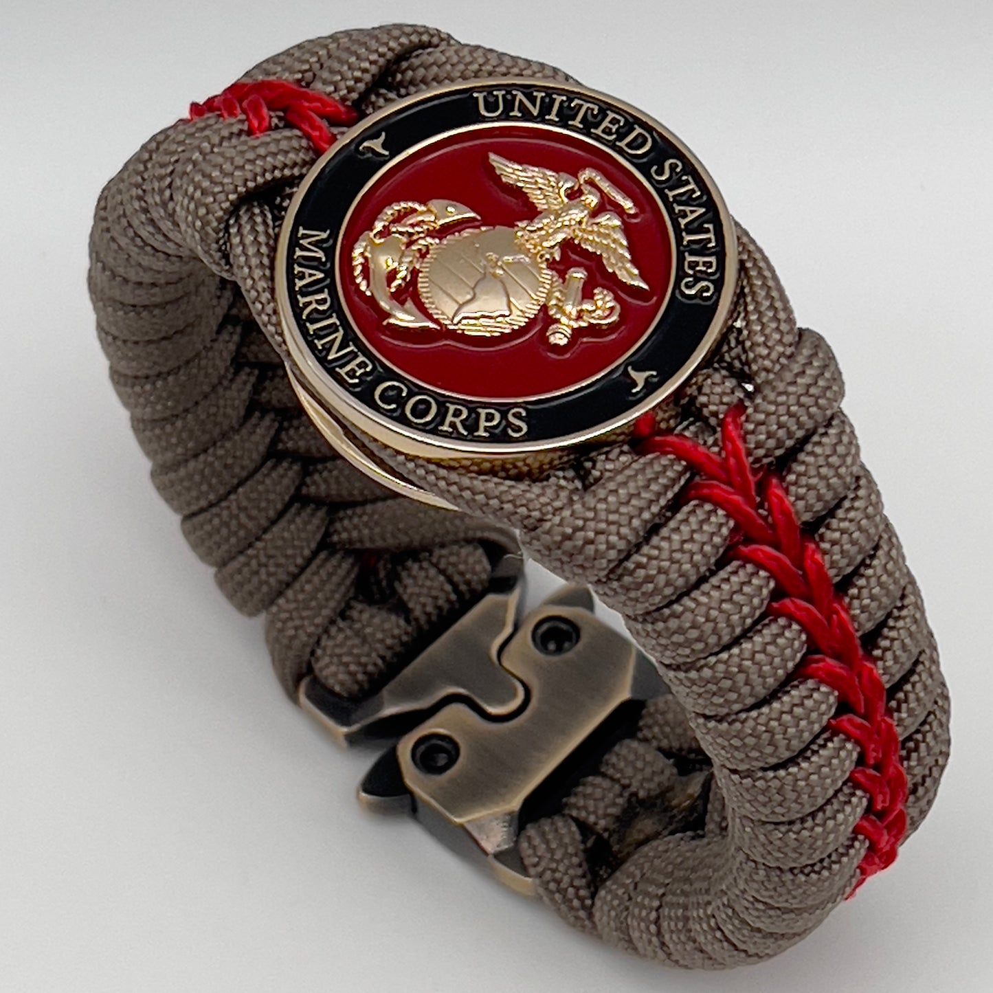 Thick, rigid and comfortable braided United States Marine Corps bracelet featuring a 24K gold plated USMC Eagle Globe and Anchor medallion, a gold Cobra style tactical buckle and woven with tan 550 paracord and Imperial Red micro cord.
