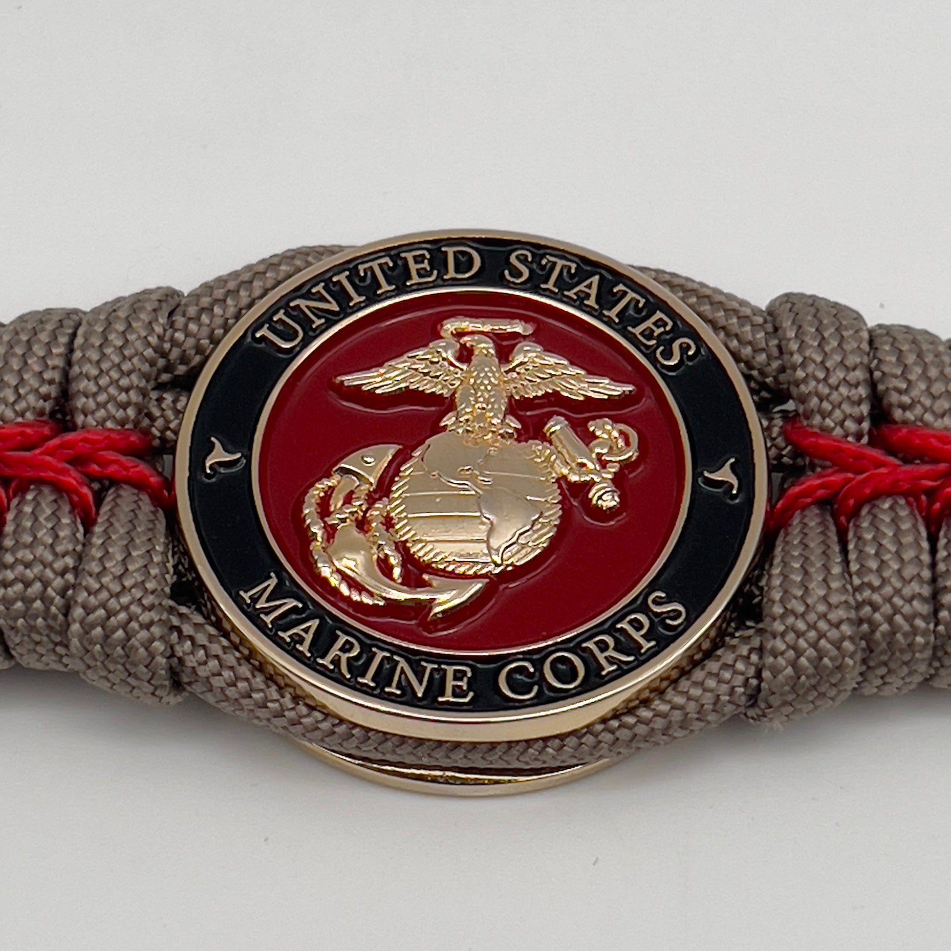 Thick, rigid and comfortable braided United States Marine Corps bracelet featuring a 24K gold plated USMC Eagle Globe and Anchor medallion, a gold Cobra style tactical buckle and woven with tan 550 paracord and Imperial Red micro cord.