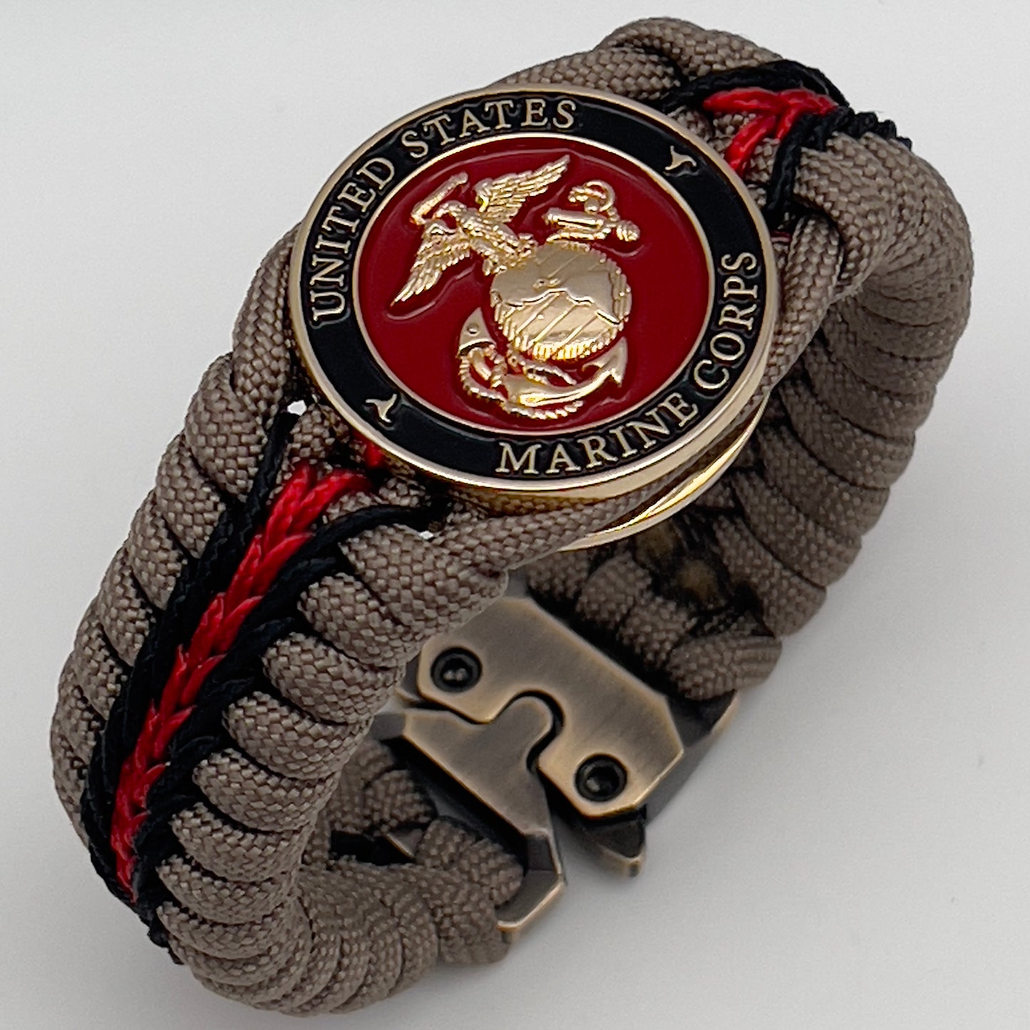Thick, rigid and comfortable braided United States Marine Corps bracelet featuring a 24K gold plated USMC Eagle Globe and Anchor medallion, a gold Cobra style tactical buckle and woven with tan 550 paracord and Imperial Red and black micro cord.