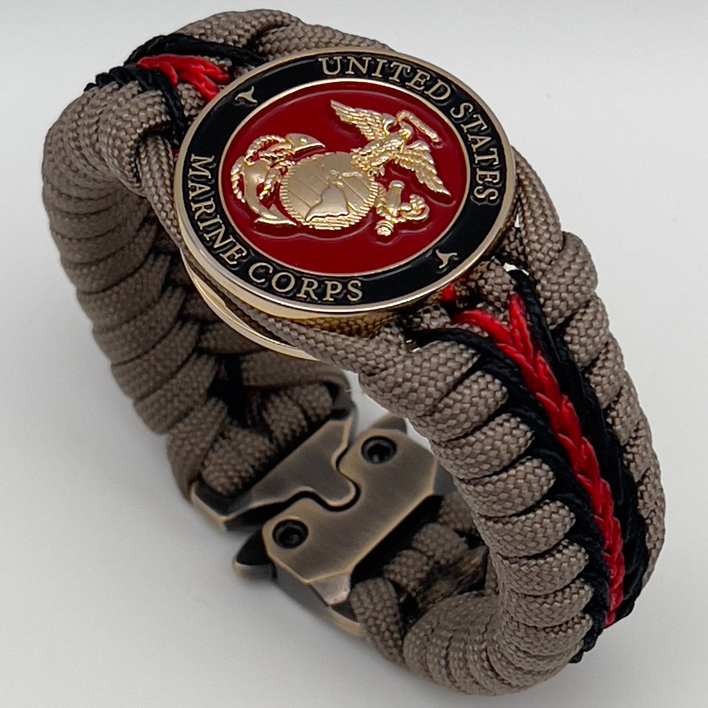 Thick, rigid and comfortable braided United States Marine Corps bracelet featuring a 24K gold plated USMC Eagle Globe and Anchor medallion, a gold Cobra style tactical buckle and woven with tan 550 paracord and Imperial Red and black micro cord.