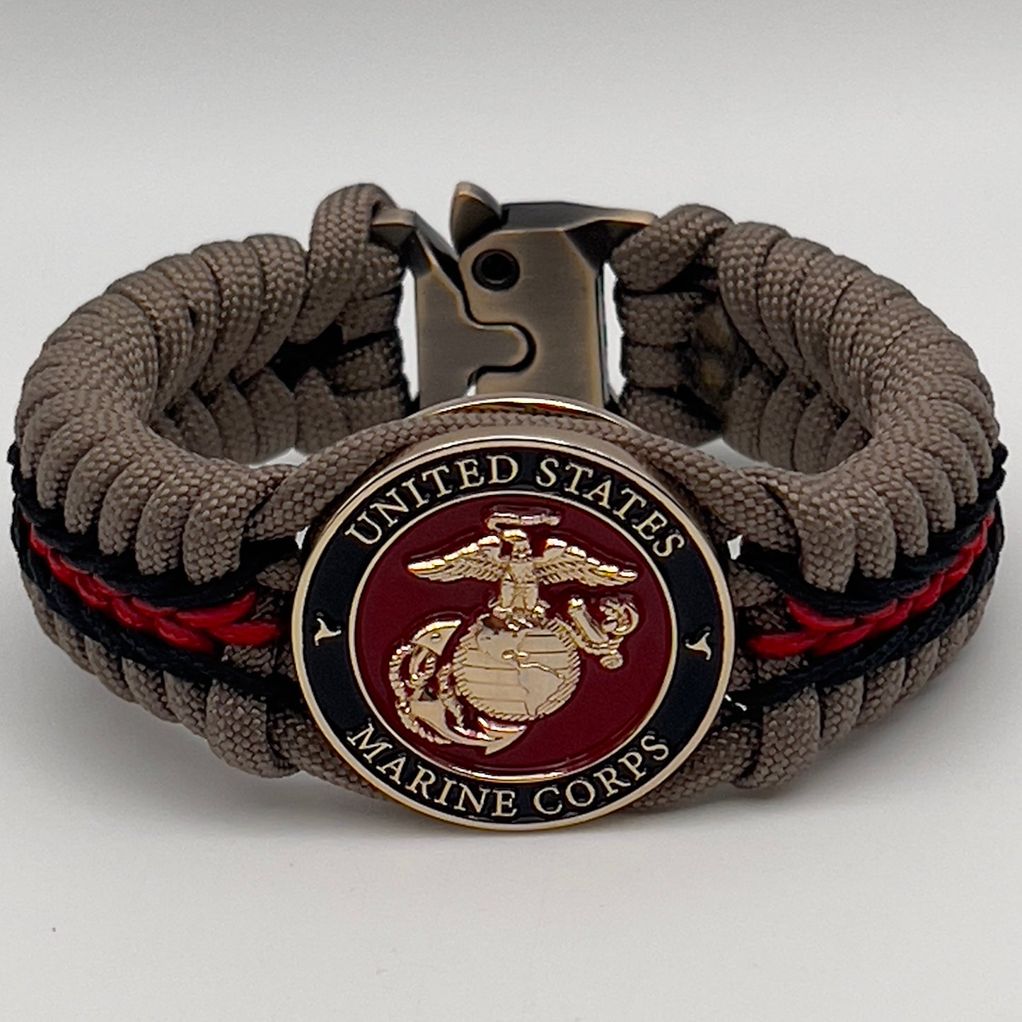 Thick, rigid and comfortable braided United States Marine Corps bracelet featuring a 24K gold plated USMC Eagle Globe and Anchor medallion, a gold Cobra style tactical buckle and woven with tan 550 paracord and Imperial Red and black micro cord.