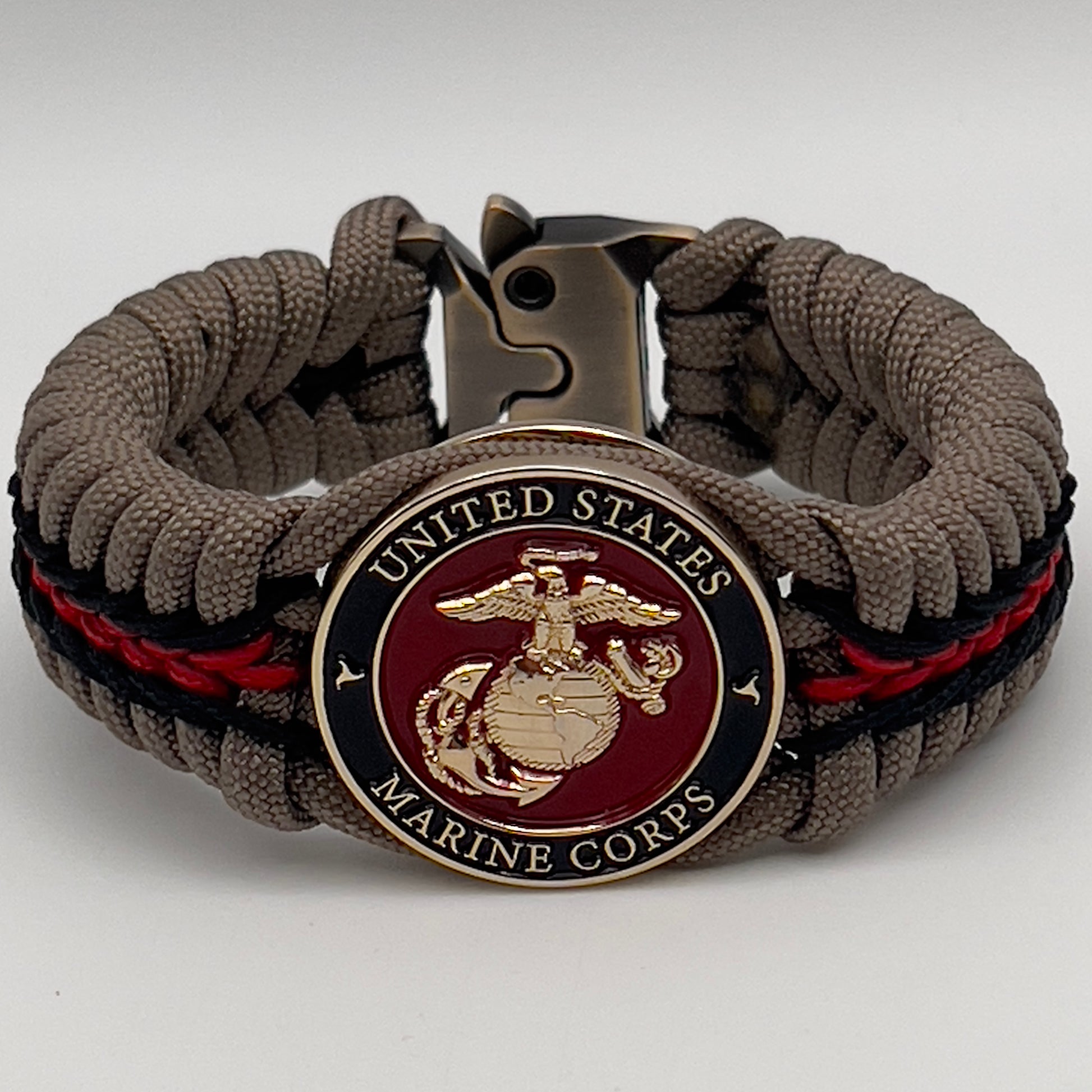 Thick, rigid and comfortable braided United States Marine Corps bracelet featuring a 24K gold plated USMC Eagle Globe and Anchor medallion, a gold Cobra style tactical buckle and woven with tan 550 paracord and Imperial Red and black micro cord.