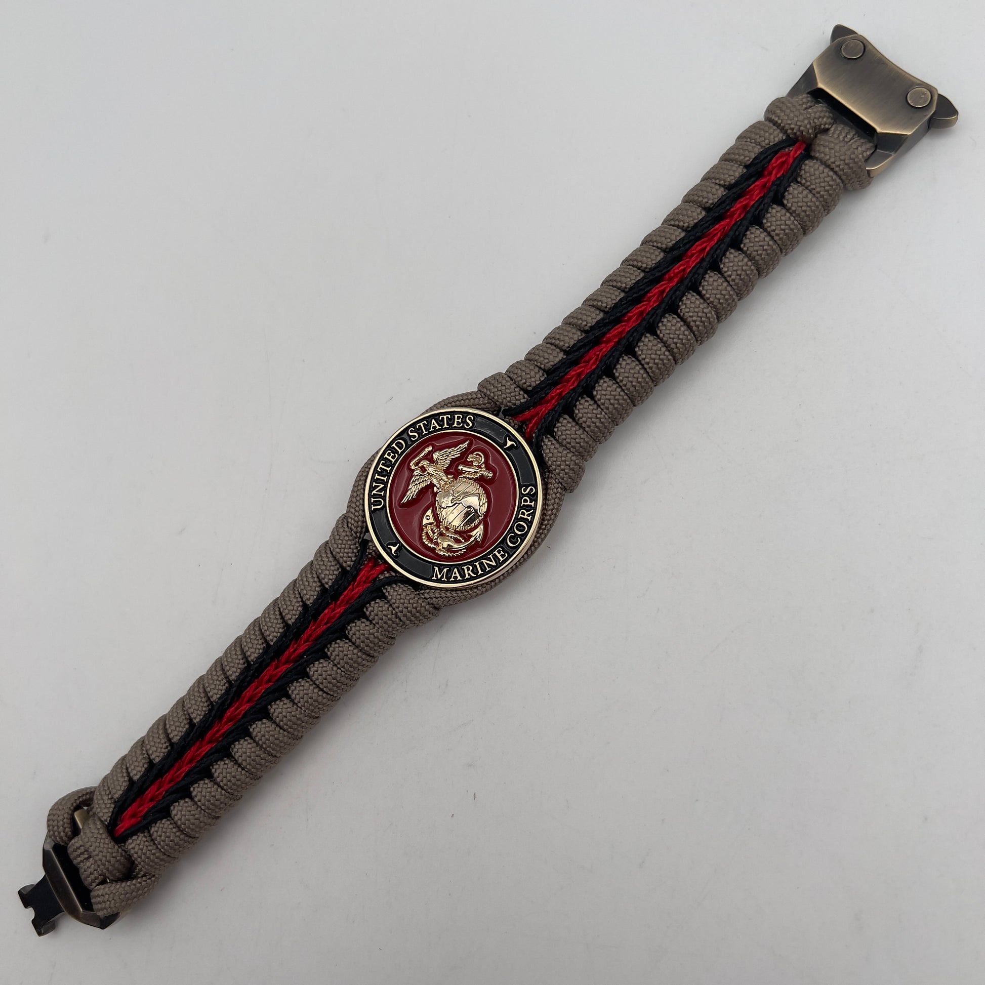 Thick, rigid and comfortable braided United States Marine Corps bracelet featuring a 24K gold plated USMC Eagle Globe and Anchor medallion, a gold Cobra style tactical buckle and woven with tan 550 paracord and Imperial Red and black micro cord.