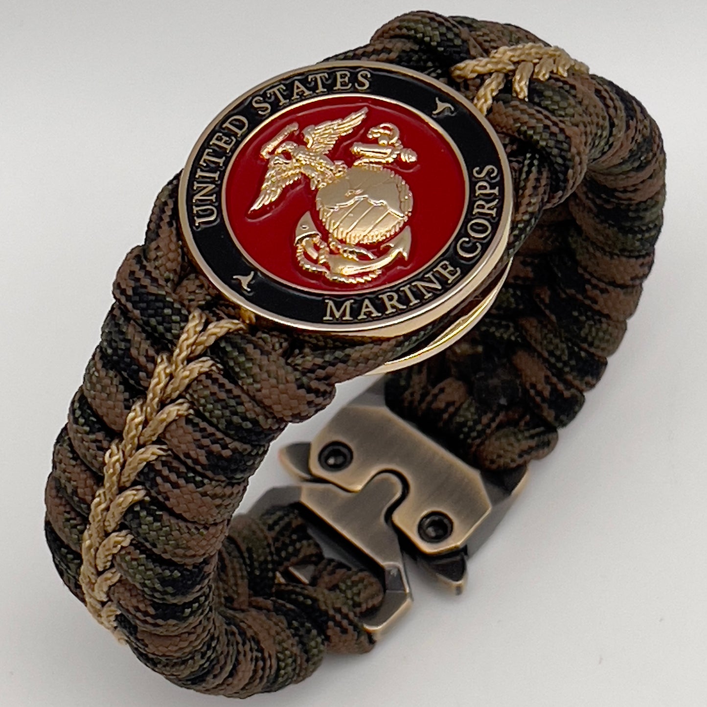Thick, rigid and comfortable braided United States Marine Corps bracelet featuring a 24K gold plated USMC Eagle Globe and Anchor medallion, a gold Cobra style tactical buckle and woven with Woodland 550 paracord.