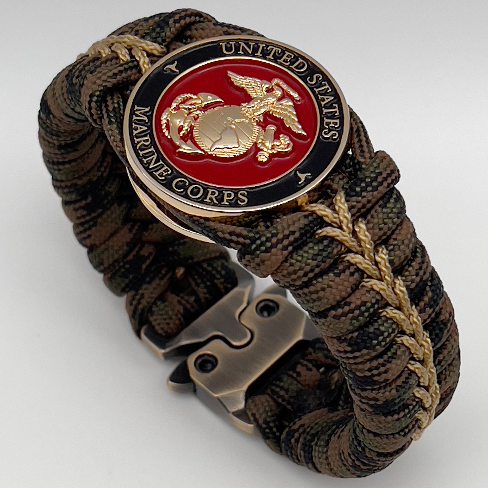 Thick, rigid and comfortable braided United States Marine Corps bracelet featuring a 24K gold plated USMC Eagle Globe and Anchor medallion, a gold Cobra style tactical buckle and woven with Woodland 550 paracord.