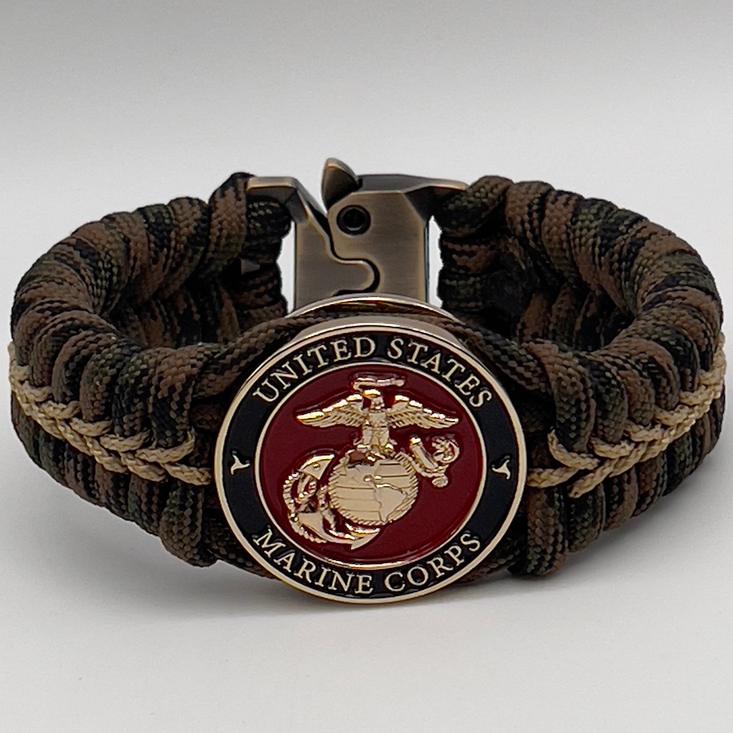 Thick, rigid and comfortable braided United States Marine Corps bracelet featuring a 24K gold plated USMC Eagle Globe and Anchor medallion, a gold Cobra style tactical buckle and woven with Woodland 550 paracord.