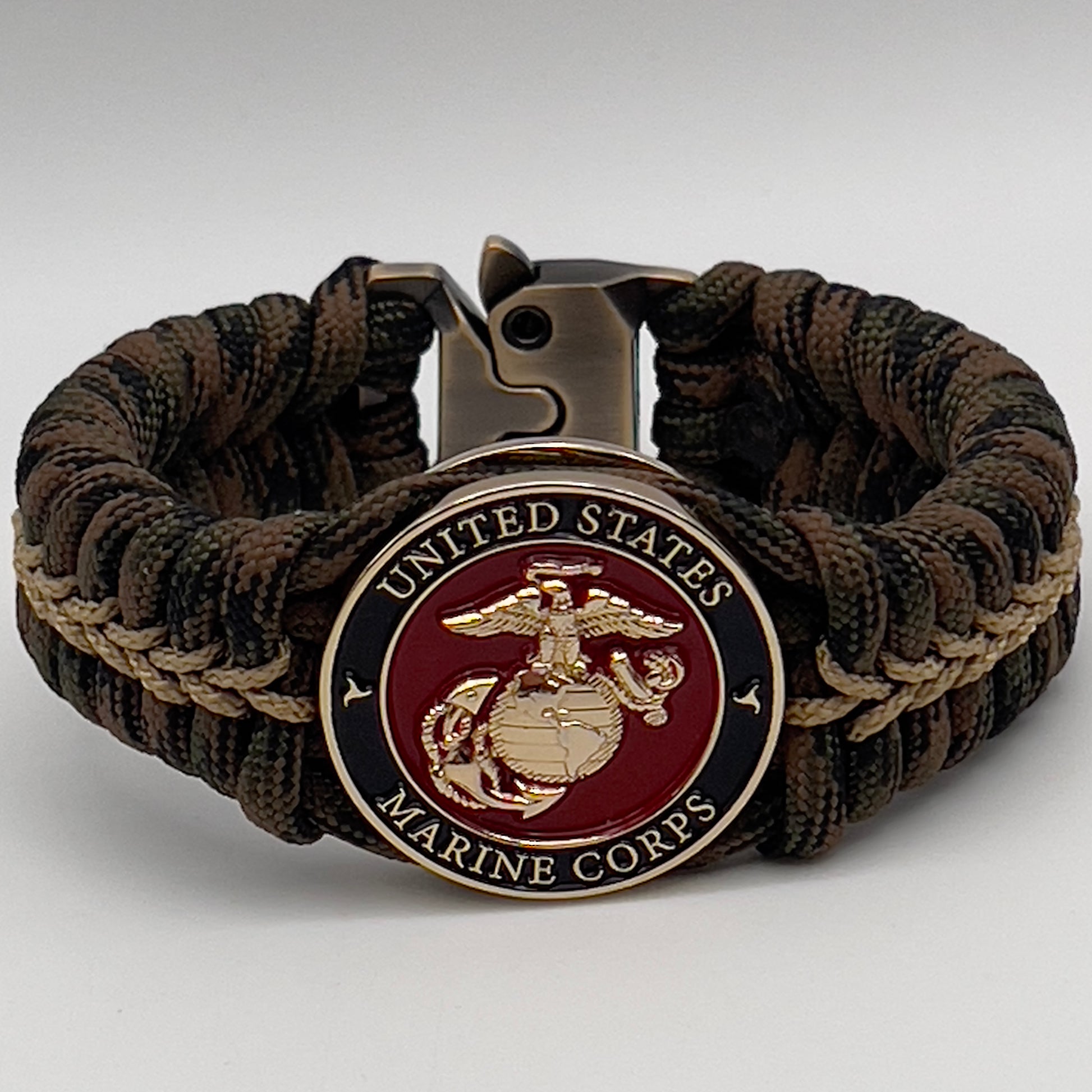 Thick, rigid and comfortable braided United States Marine Corps bracelet featuring a 24K gold plated USMC Eagle Globe and Anchor medallion, a gold Cobra style tactical buckle and woven with Woodland 550 paracord.