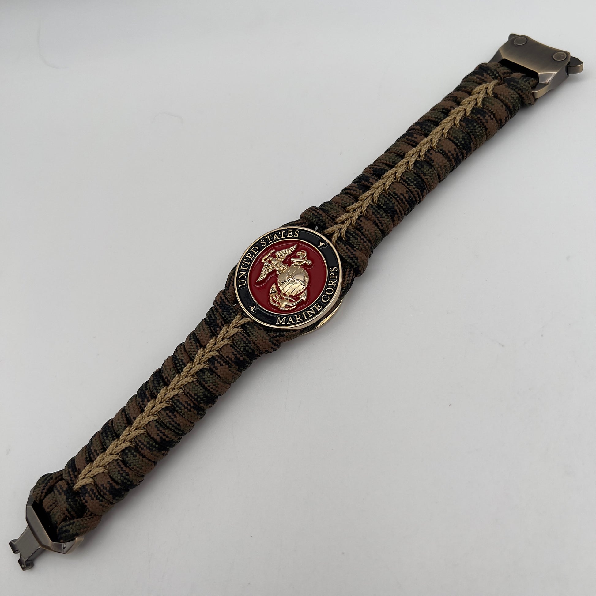 Thick, rigid and comfortable braided United States Marine Corps bracelet featuring a 24K gold plated USMC Eagle Globe and Anchor medallion, a gold Cobra style tactical buckle and woven with Woodland 550 paracord.