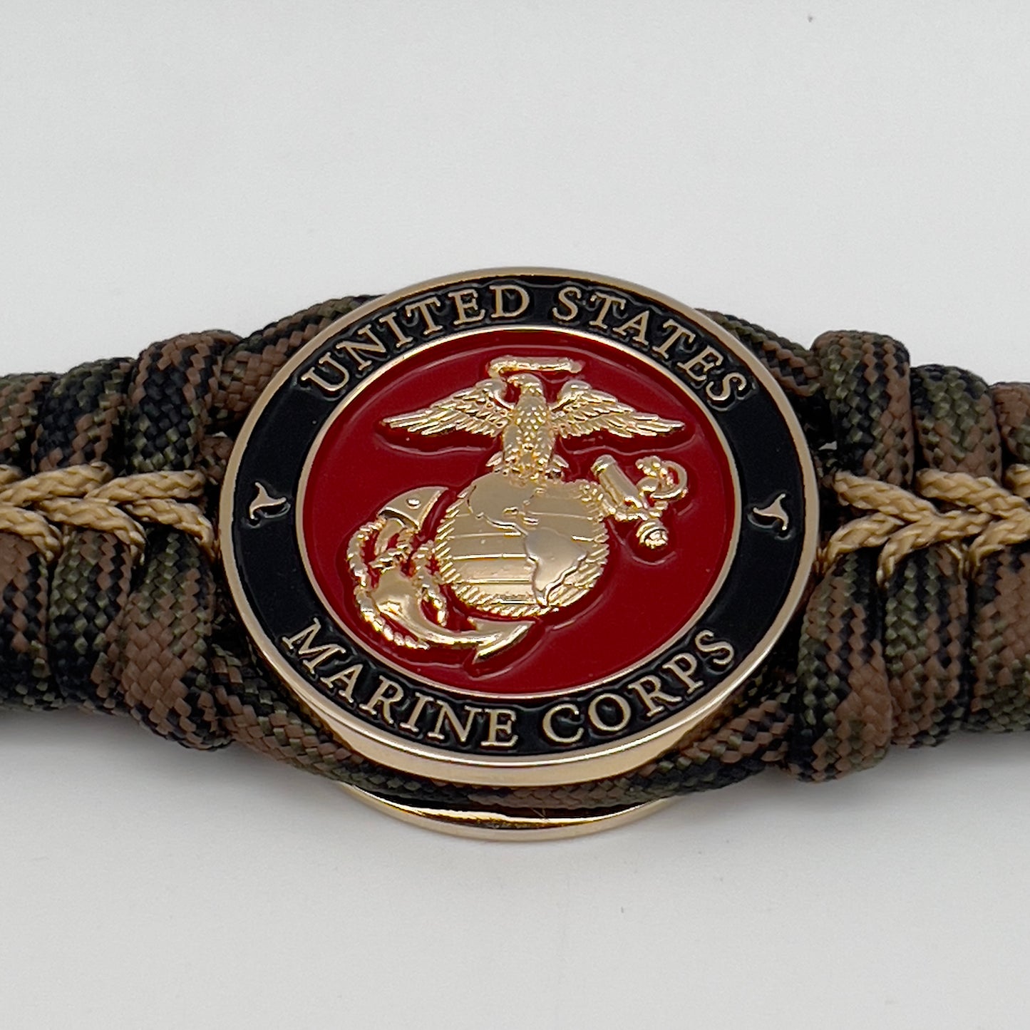 Thick, rigid and comfortable braided United States Marine Corps bracelet featuring a 24K gold plated USMC Eagle Globe and Anchor medallion, a gold Cobra style tactical buckle and woven with Woodland 550 paracord.