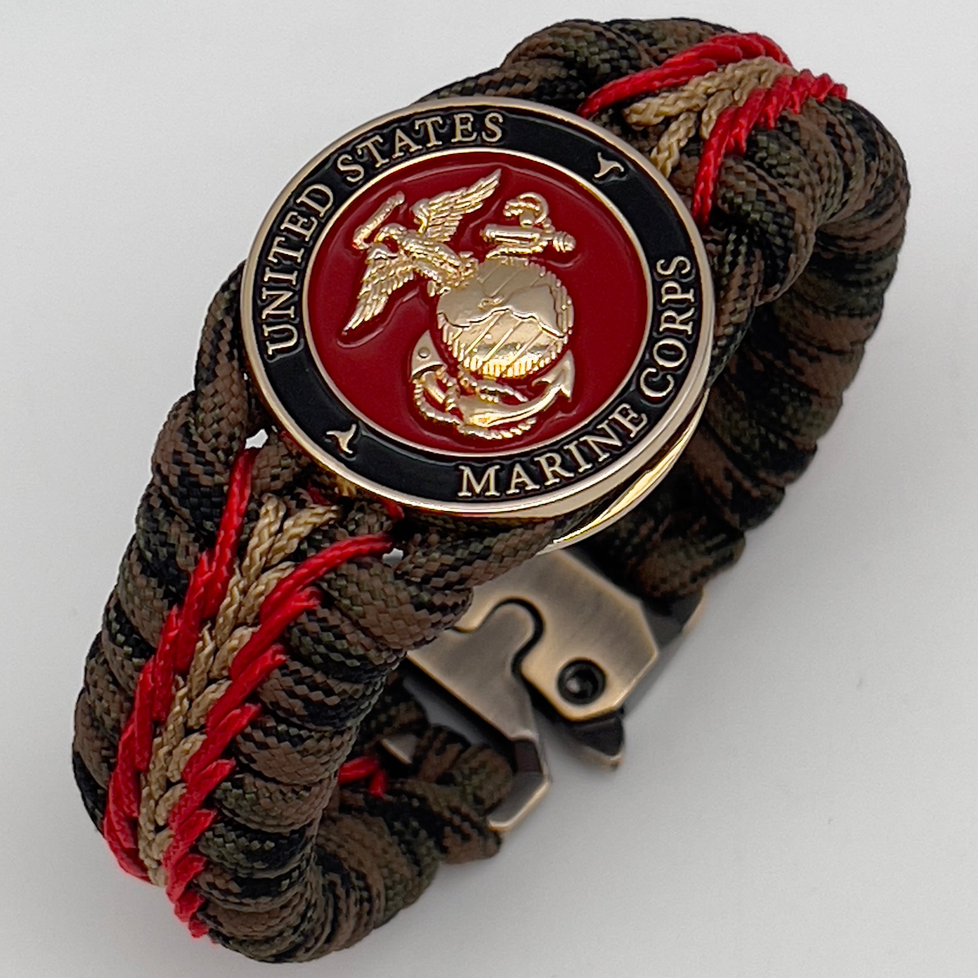 Thick, rigid and comfortable braided United States Marine Corps bracelet featuring a 24K gold plated USMC Eagle Globe and Anchor medallion, a gold Cobra style tactical buckle and woven with Woodland camo 550 paracord and Imperial Red and Gold micro cord.