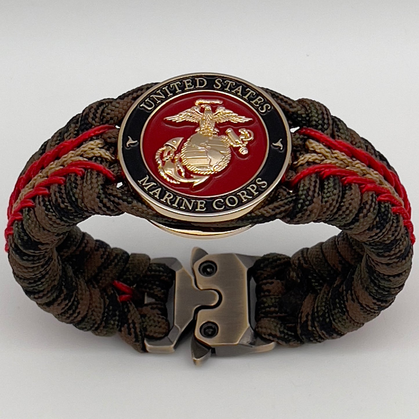 Thick, rigid and comfortable braided United States Marine Corps bracelet featuring a 24K gold plated USMC Eagle Globe and Anchor medallion, a gold Cobra style tactical buckle and woven with Woodland camo 550 paracord and Imperial Red and Gold micro cord.