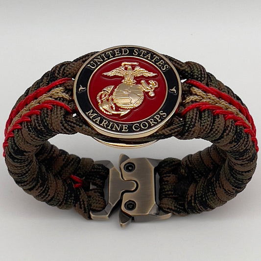 Thick, rigid and comfortable braided United States Marine Corps bracelet featuring a 24K gold plated USMC Eagle Globe and Anchor medallion, a gold Cobra style tactical buckle and woven with Woodland camo 550 paracord and Imperial Red and Gold micro cord.